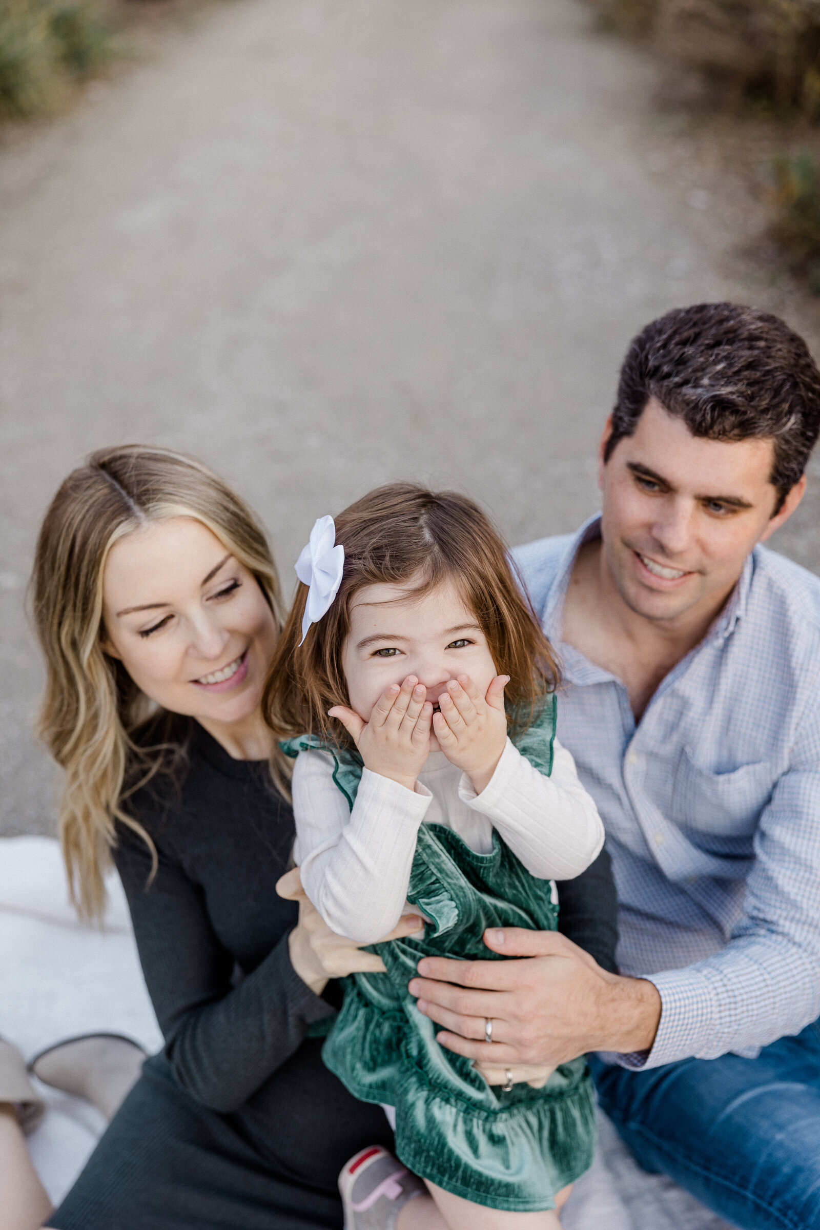 little girl giggling with her mom and dad smiling at her