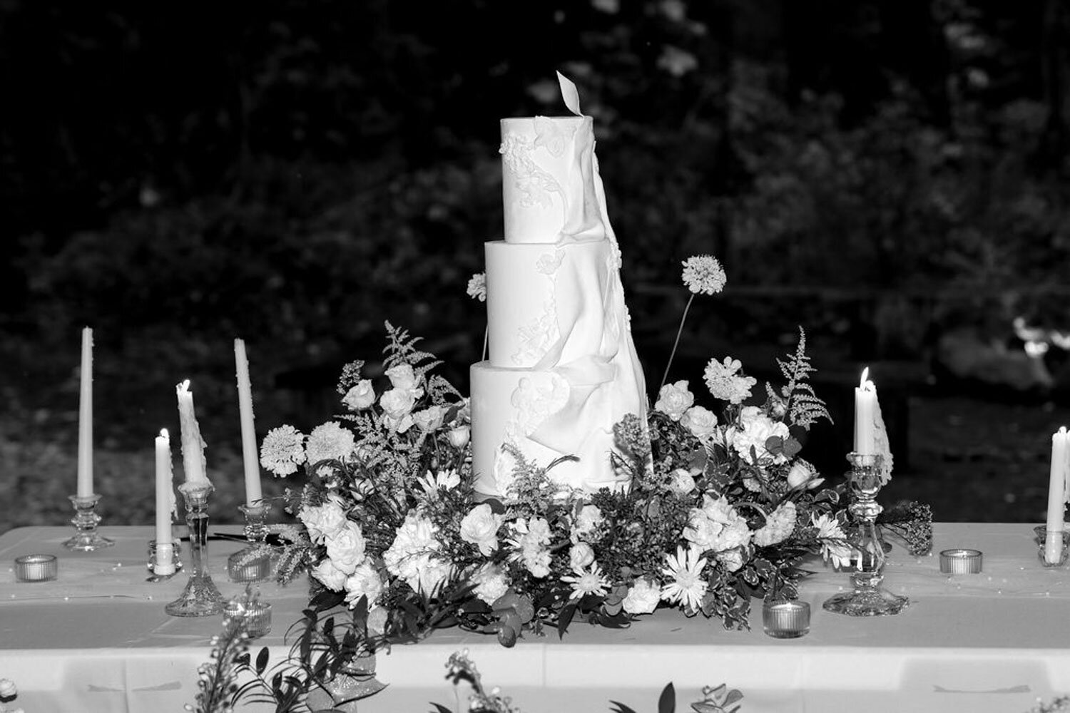 White wedding cake on a decorated table surrounded by flowers