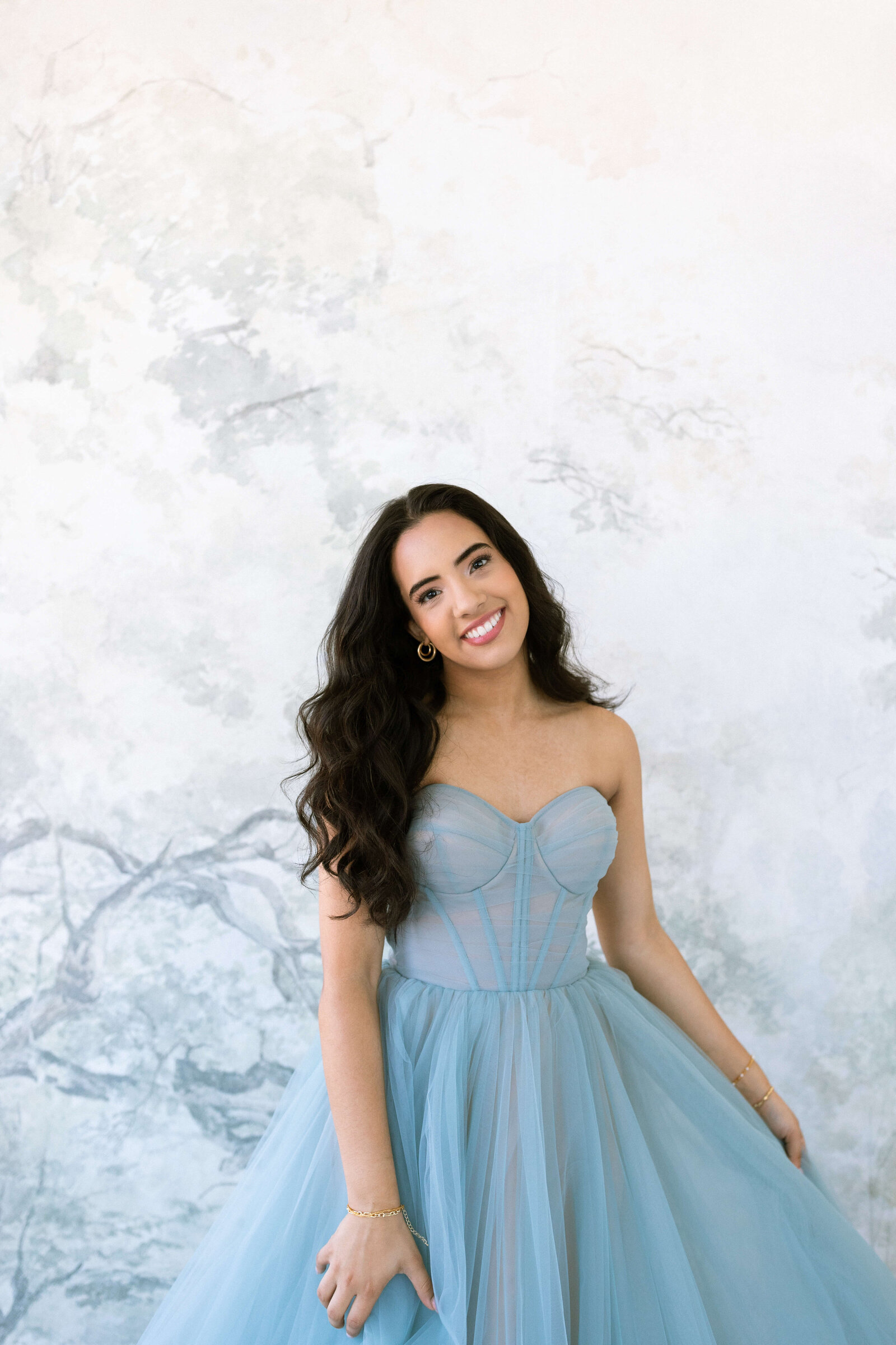 girl with dark hair posing for picture wearing a blue poofy dress
