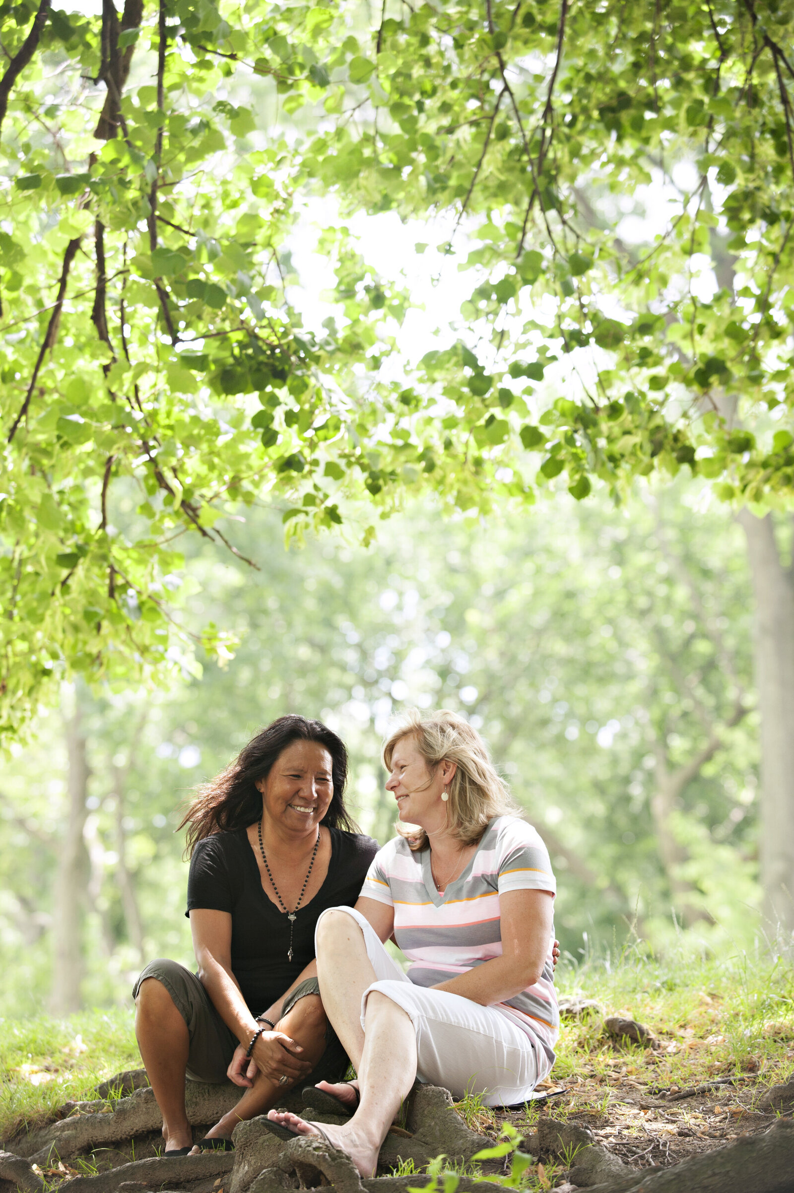 A couple sitting on the ground in a park laughing together 