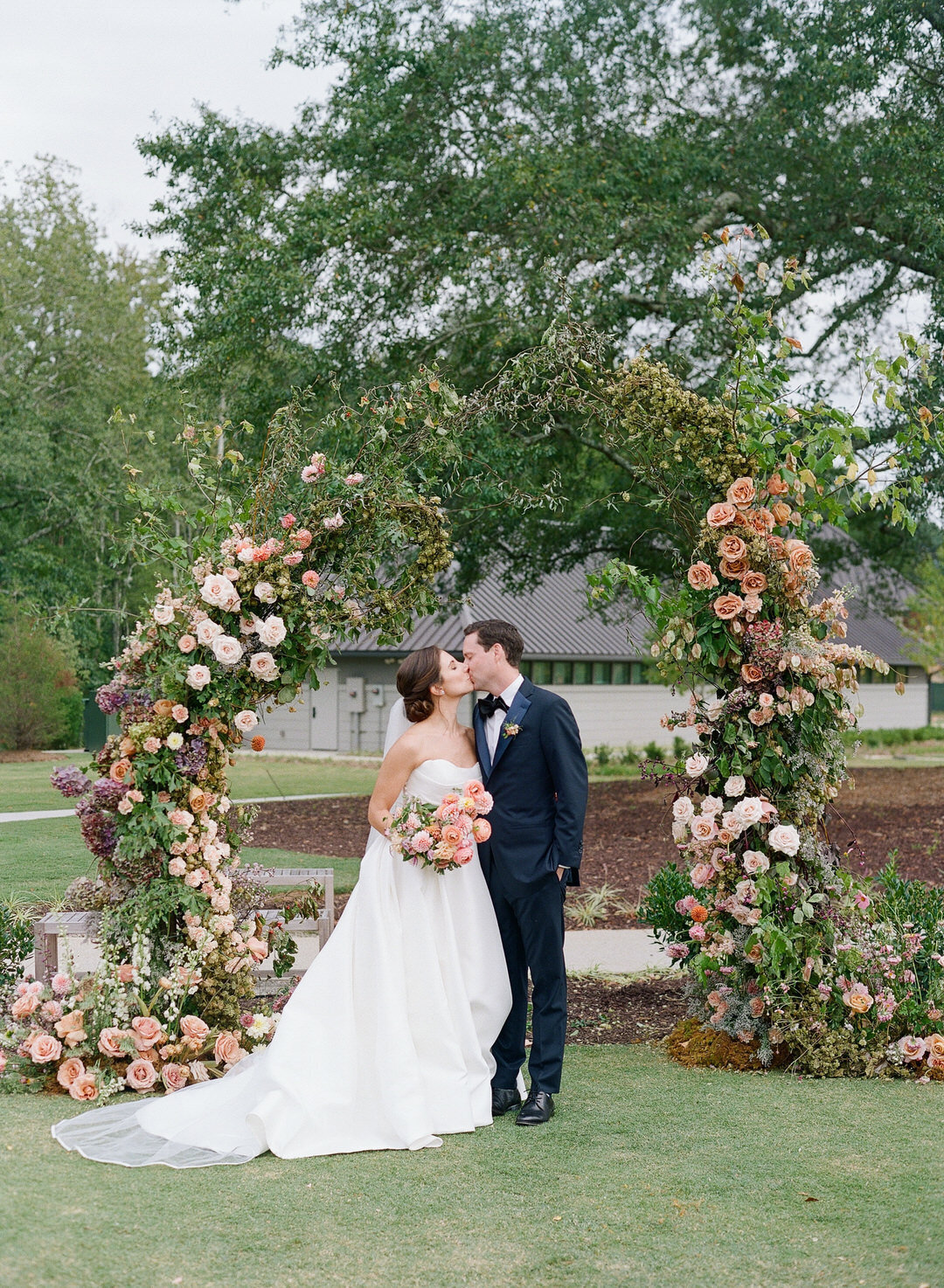 Bride and Groom Kissing in front of flower arch