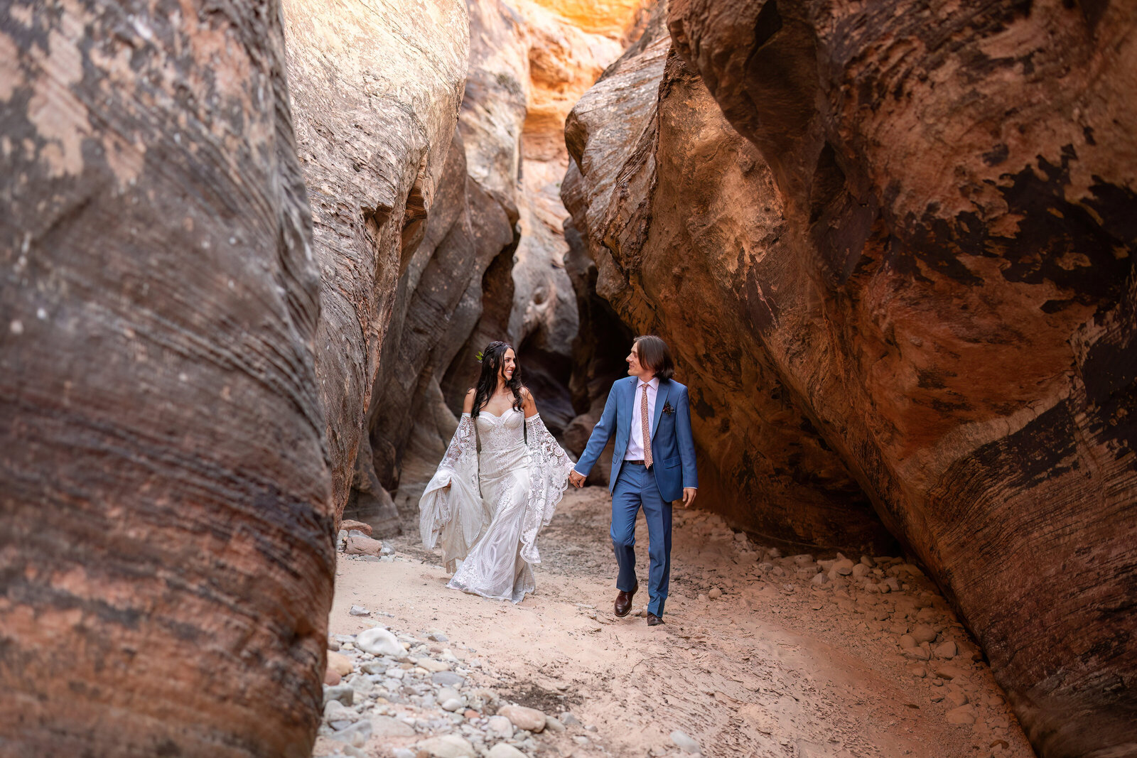 bride and groom walking in a zion slot canyon