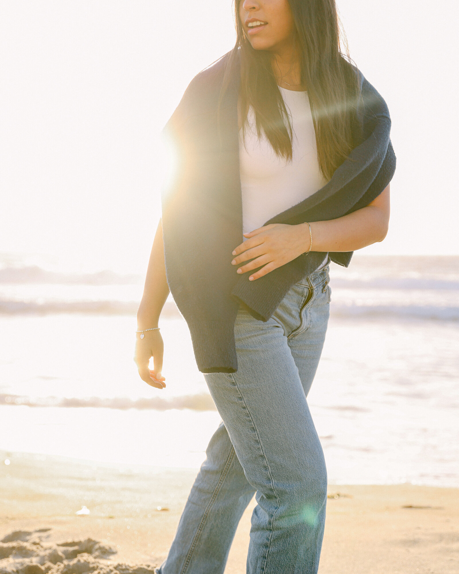 girl wearing sweater draped over shoulders in vintage levis on beach