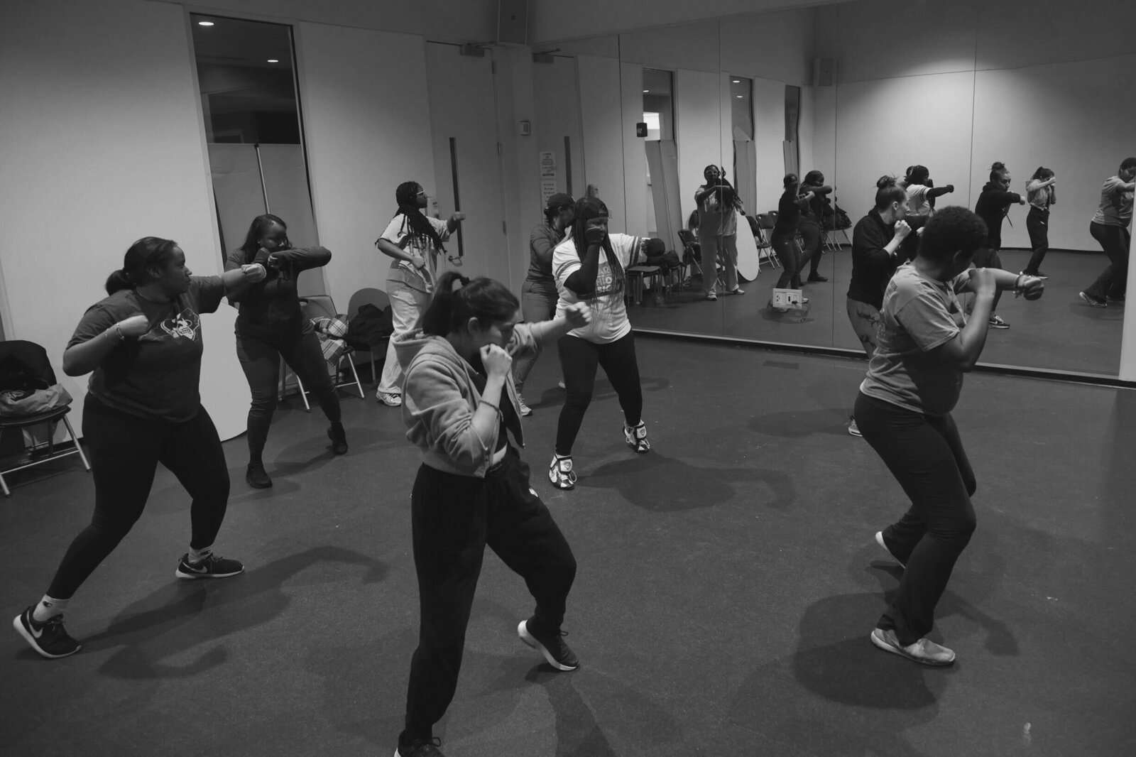 a boxing class full of women working out in front of a mirror in a gym