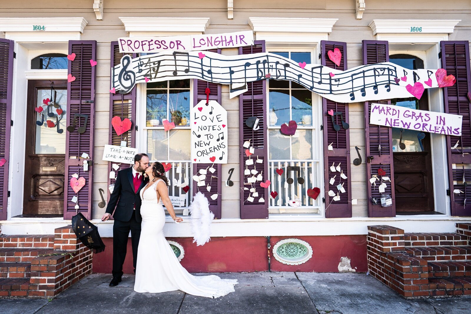 Bride and groom kiss in front of Love Letters to New Orleans house