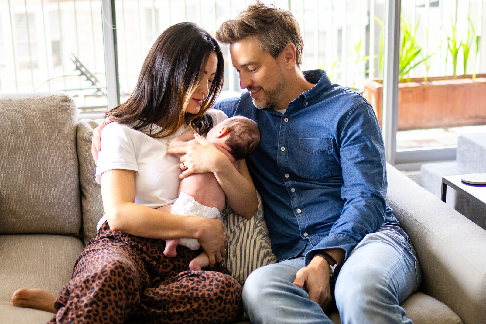 Intimate newborn family photo of parents snuggling baby on the couch – Book Bay Area Family Photographer - Ellobelle Photography