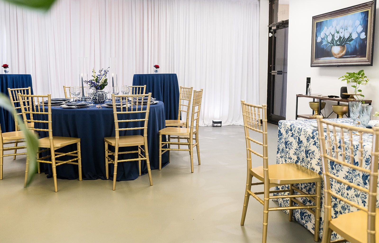 Styled table setup at The Parlor at Wells in Memphis, featuring vibrant floral centerpieces, blue toile linens, gold chairs, and natural light—ideal for showers, workshops, and private dinners.