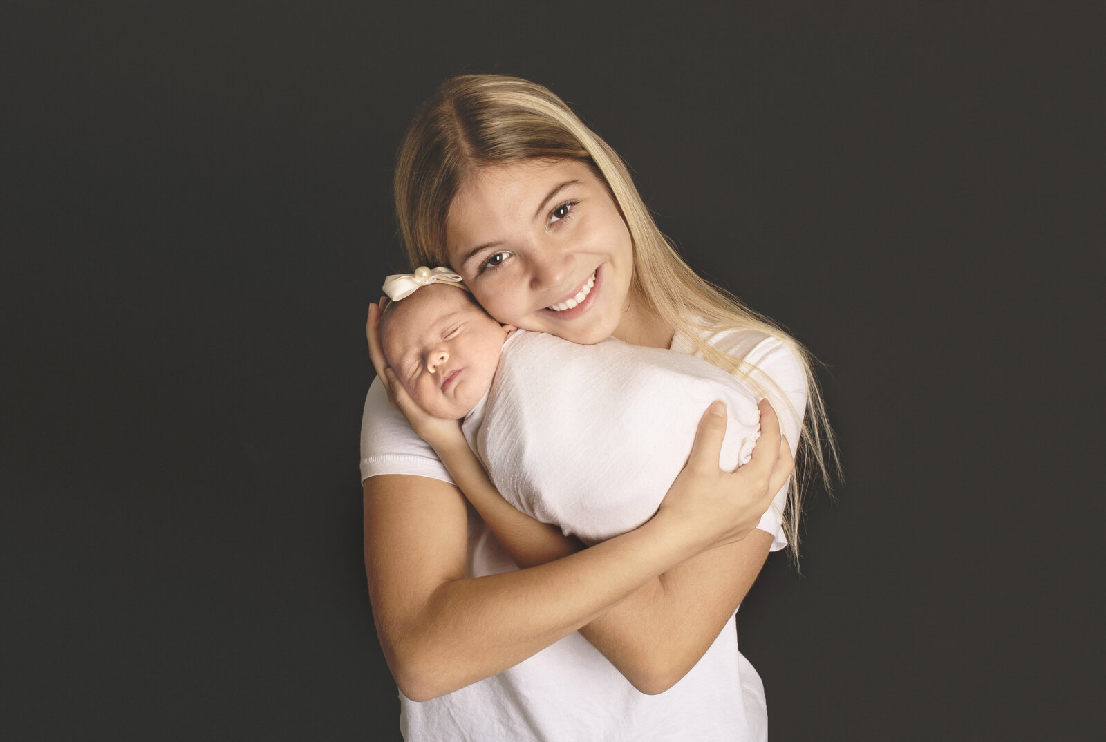 Big sister holding newborn baby sibling during newborn photoshoot with Nashville, TN photographer