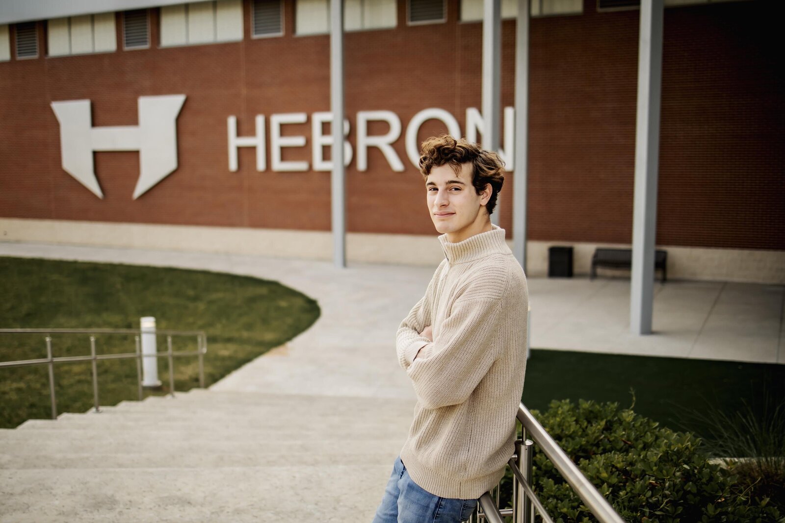 senior boy in front of Hebron High School in Lewisville ISD