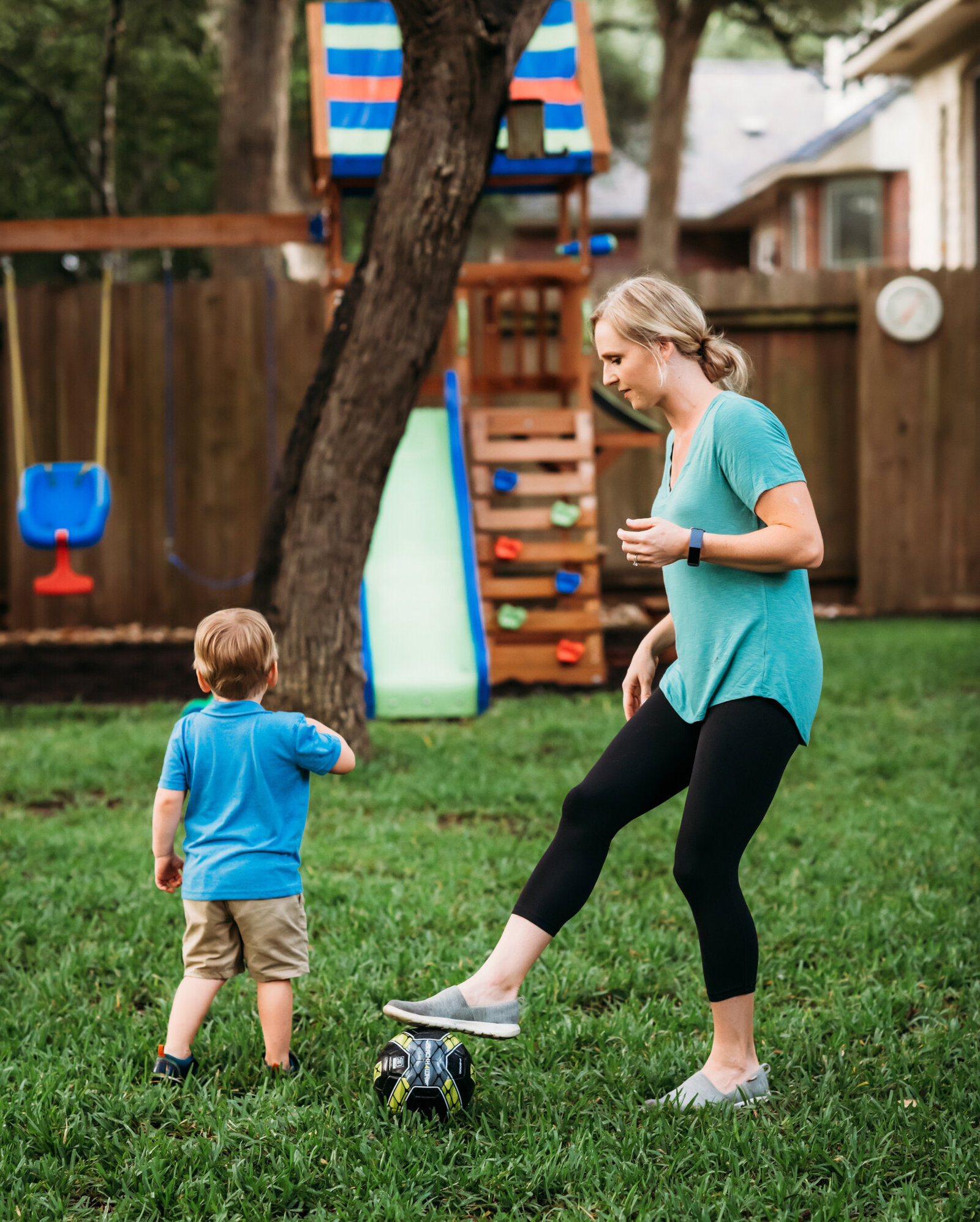 Branding Photographer,  a mother kicks around a soccer ball near her son in their yard