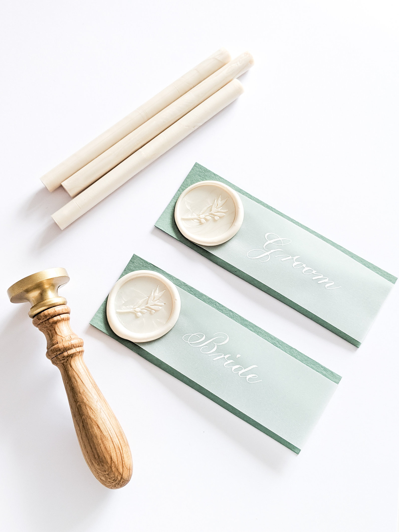 Green and white place cards with wax seal and calligraphy