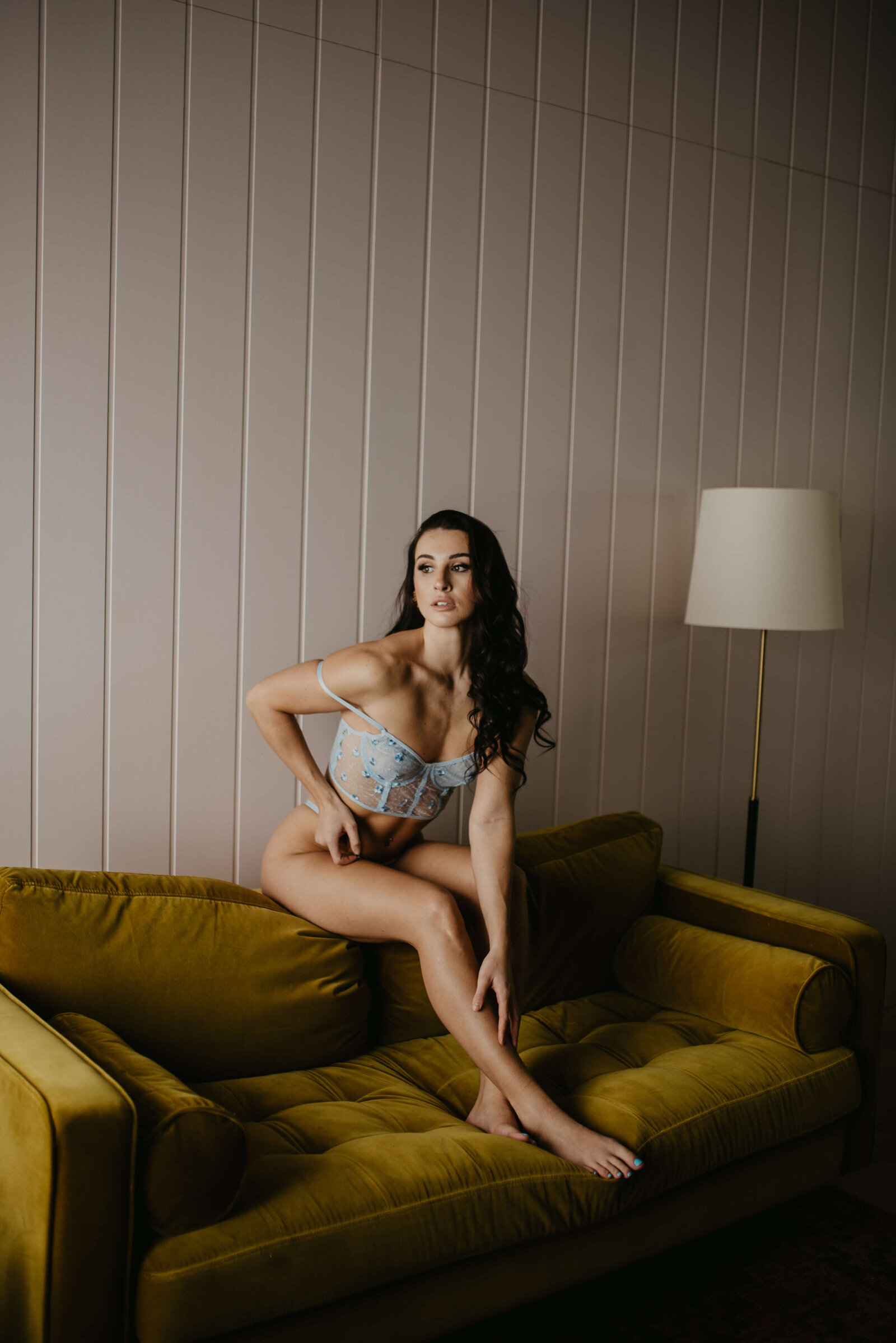 Woman sitting on the back of the couch in lingerie