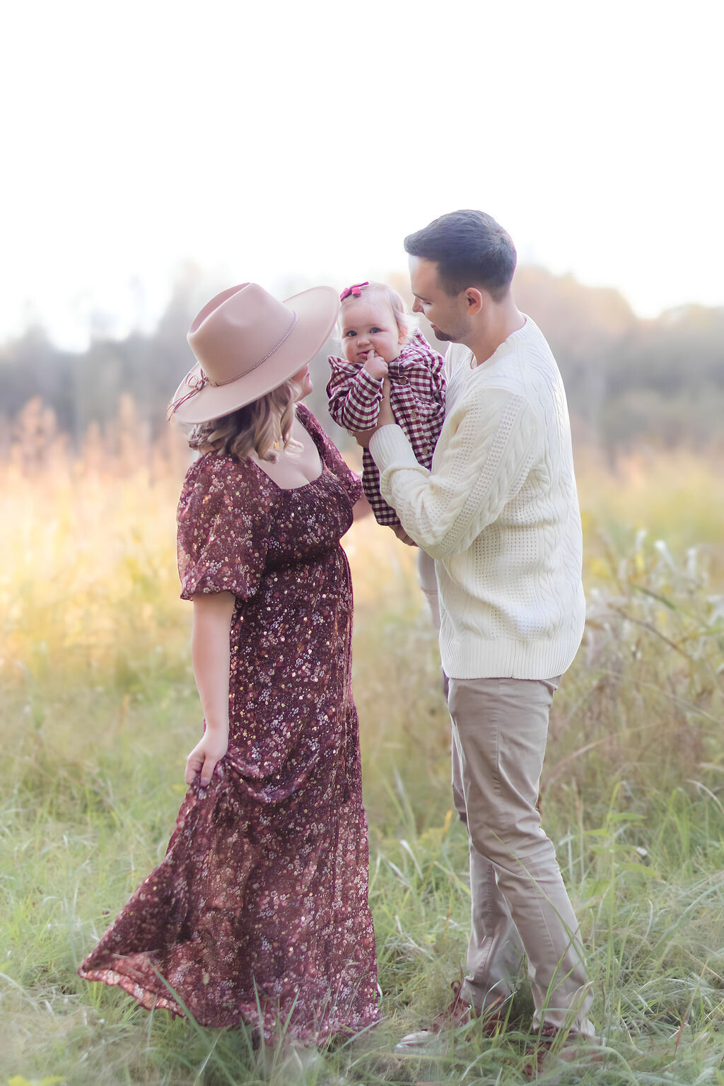 Family cuddled up together in a field with natural sunlight during a family photo session in Cornelius NC