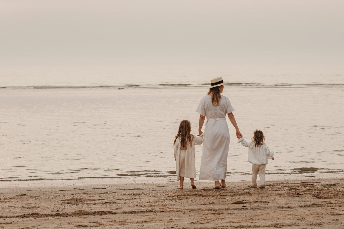 moeder en kinderen aan het strand tijdens zonsondergang