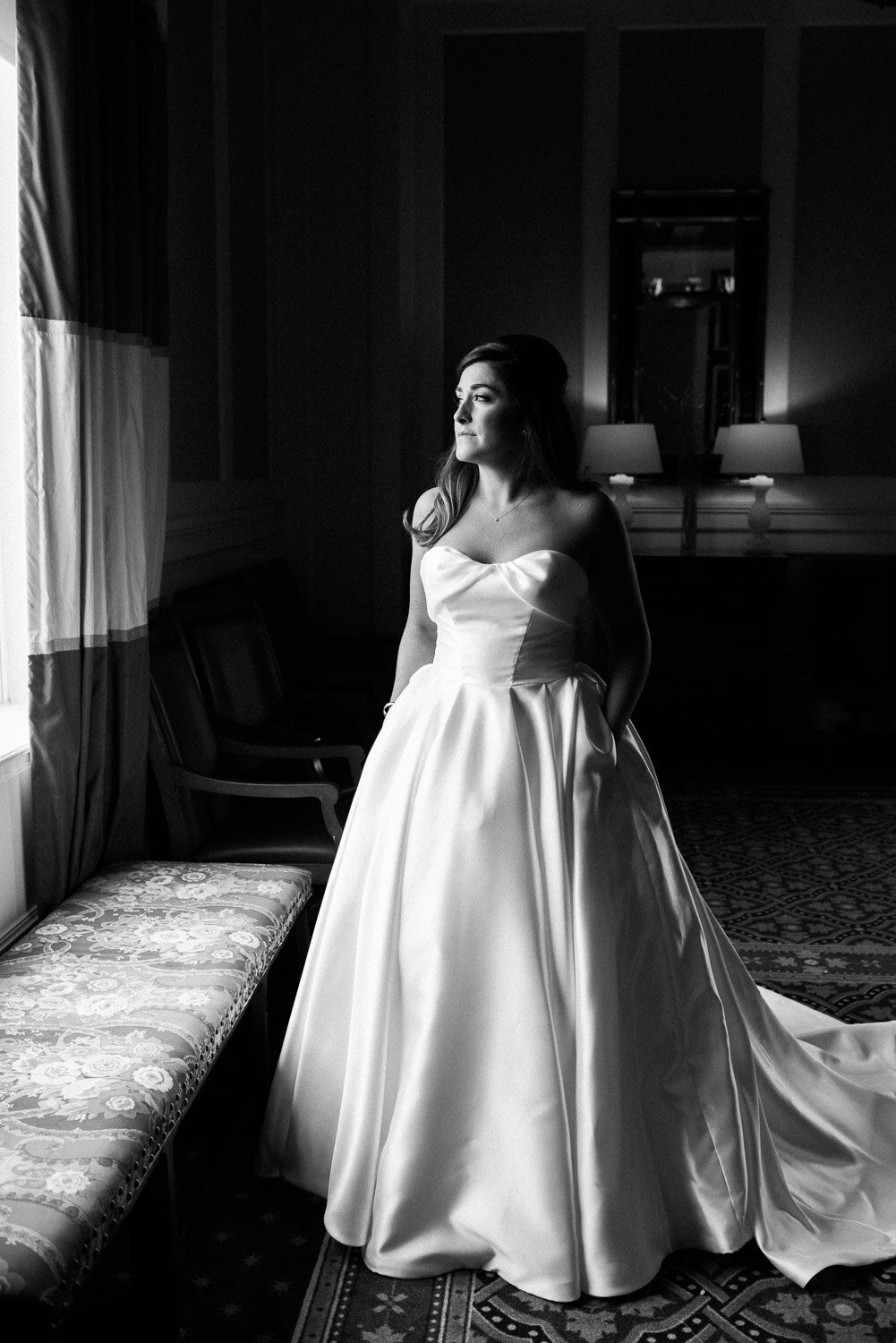 bride in gown looking out window full lenght