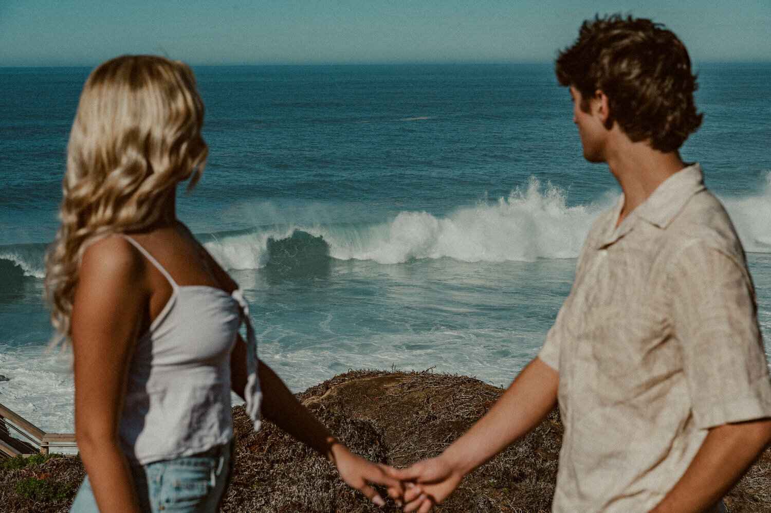 couple holding hands while watching a huge wave break in Big Sur at Garrapata State park