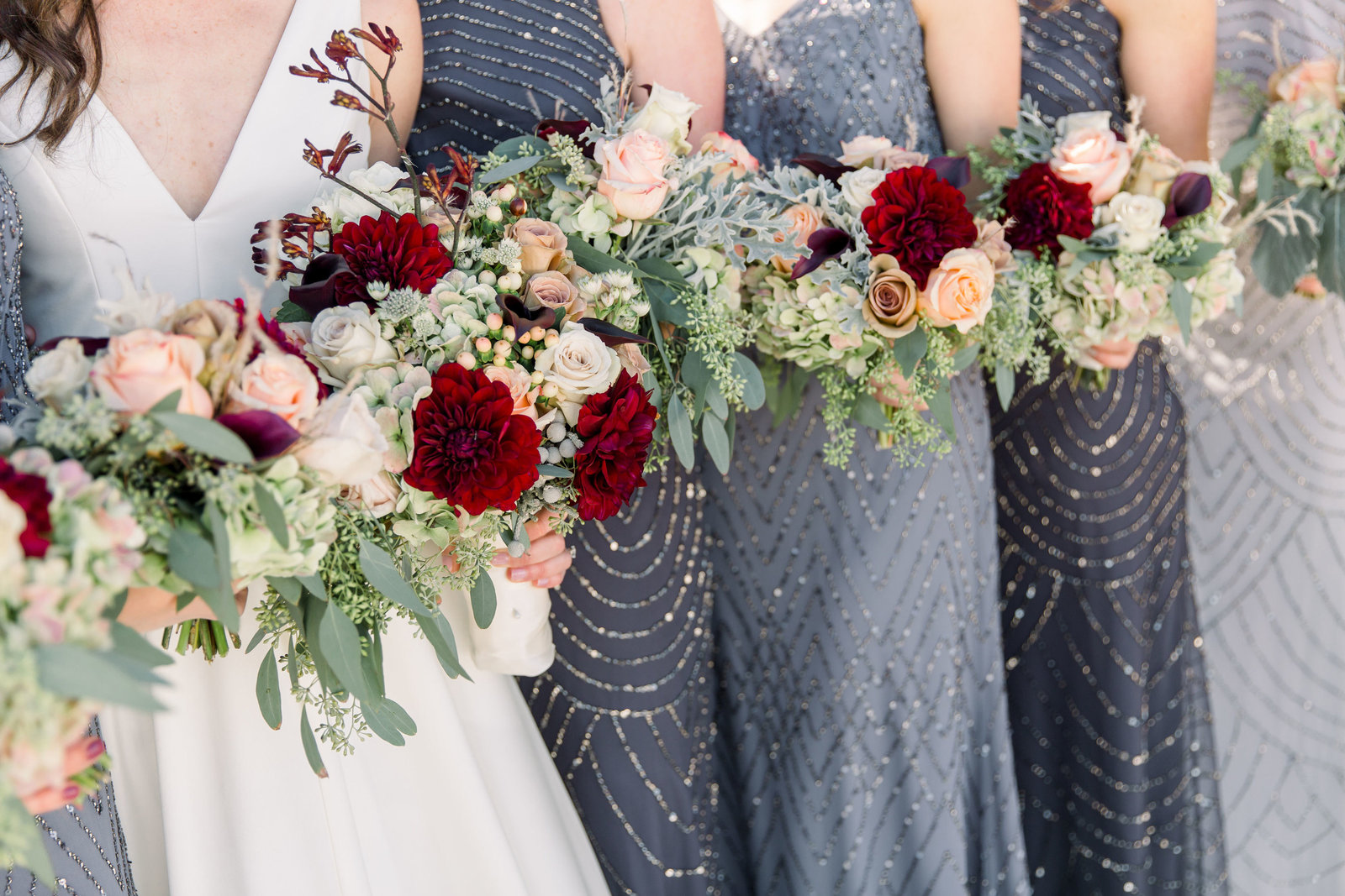 Detail image of bride and bridesmaids holding peach and red bouquets