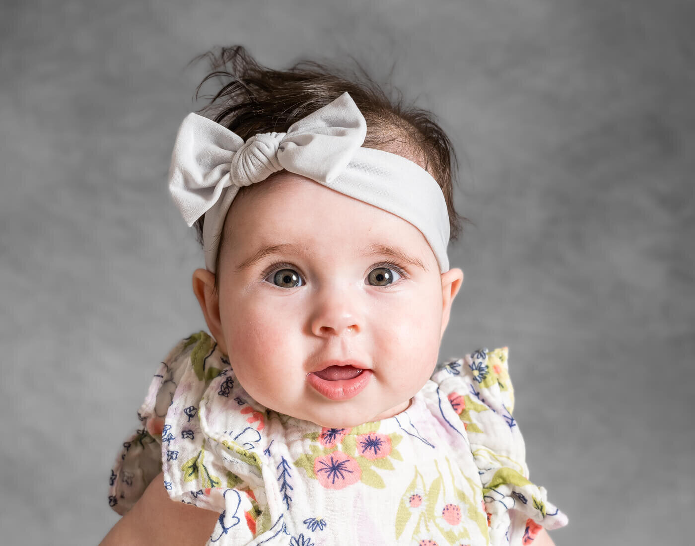 A young baby smiles, their hair disheveled.