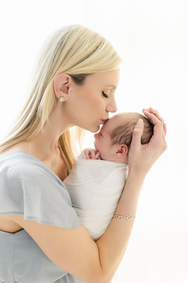 Mom kissing head of newborn baby, by newborn photography in new jersey
