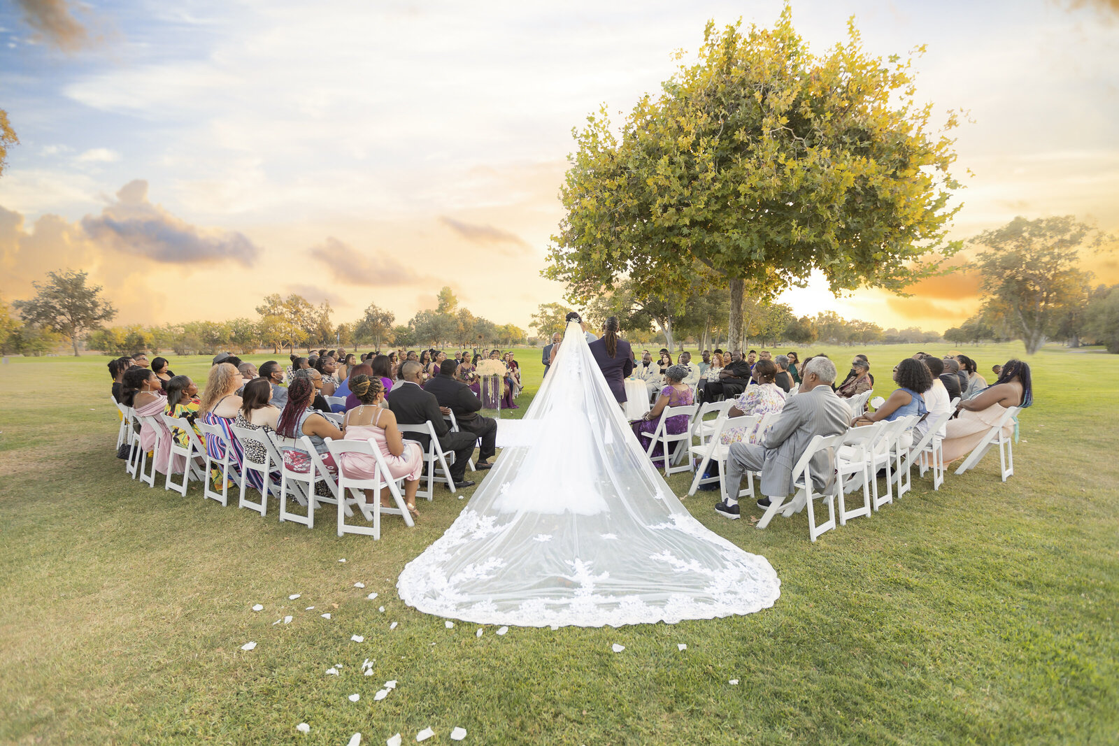 Bride walks down the aisle with guests looking on and her veil trailing behind dramatically in the Sacramento CA wedding  photograph.