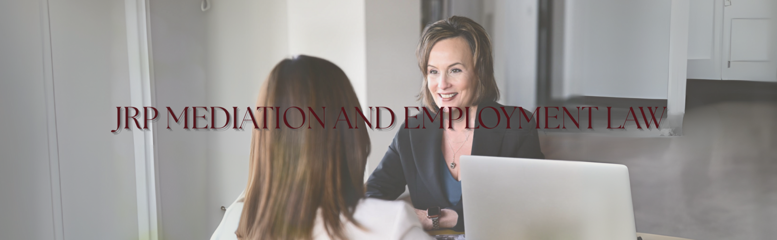 alt="Jennifer R Petersen smiling while meeting with a client in her office with a laptop, JRP Mediation and Employment Law Firm"
