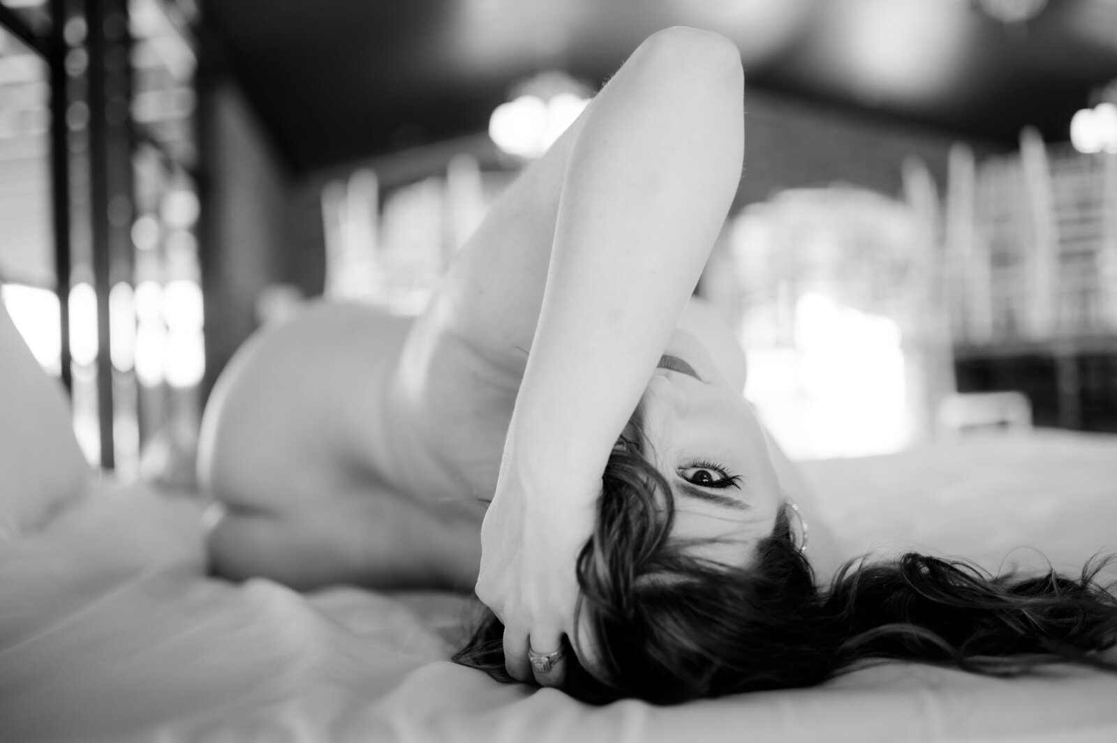 black and white boudoir photography with woman on a bed holding her hair