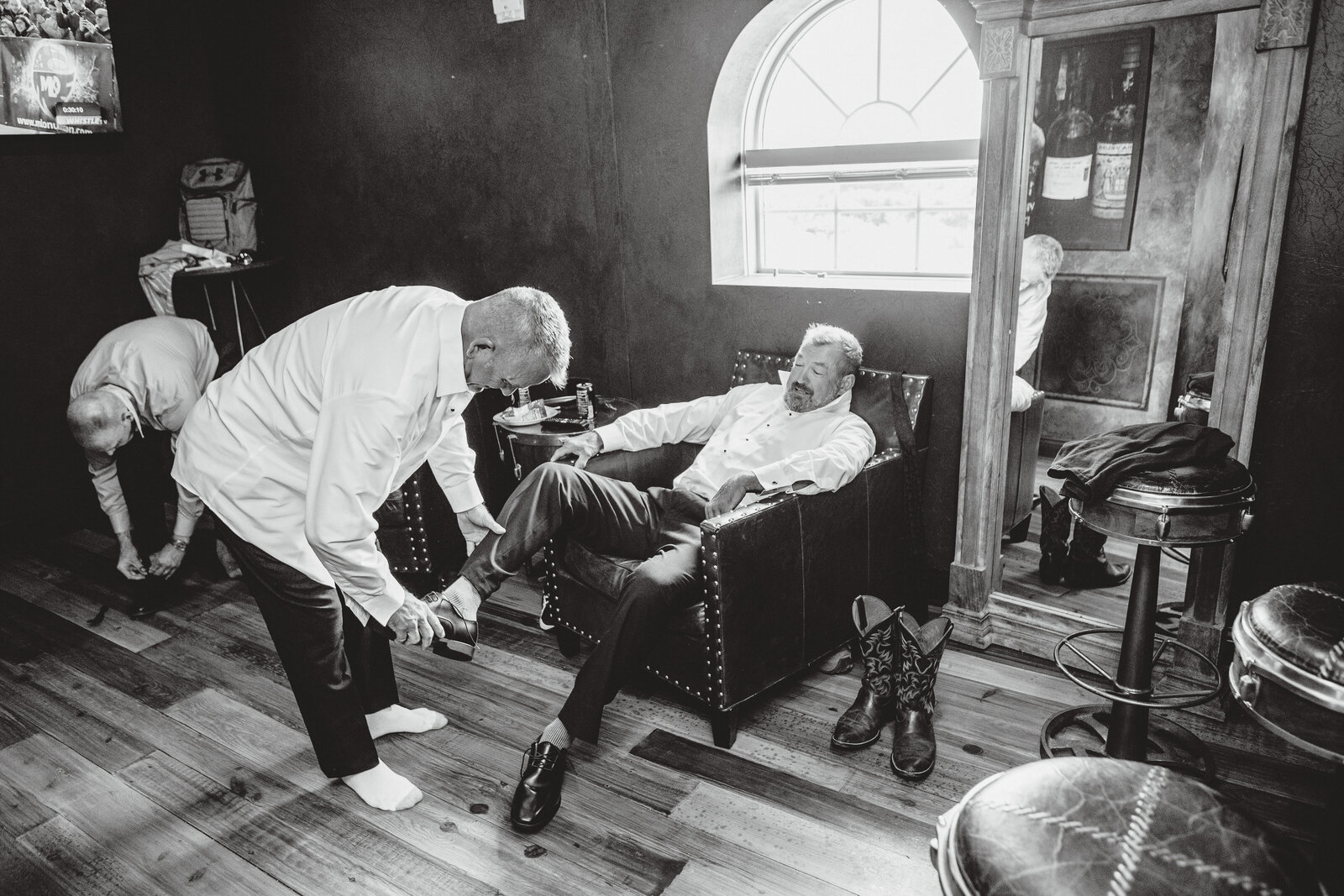 Guys helping put on shoes during a wedding