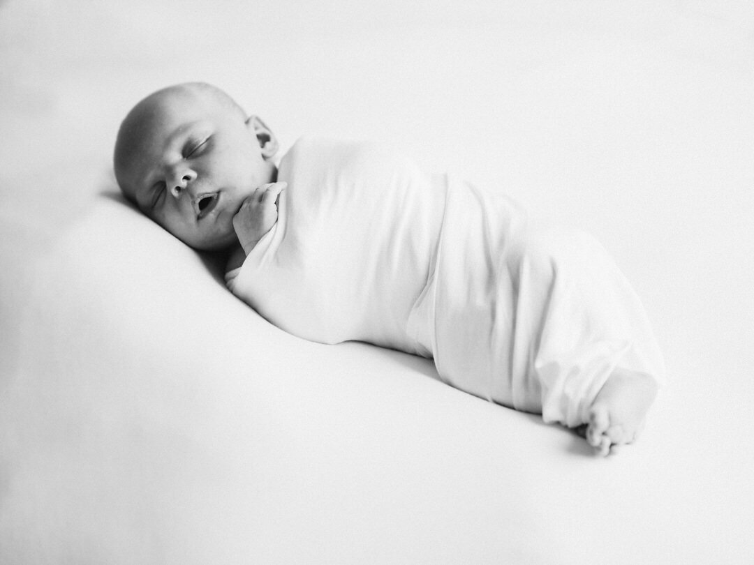 newborn baby in black and white photograph wrapped in a swaddle sleeping