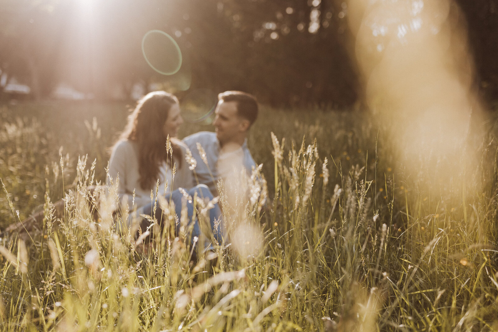 A man and woman sit together in a sunny field