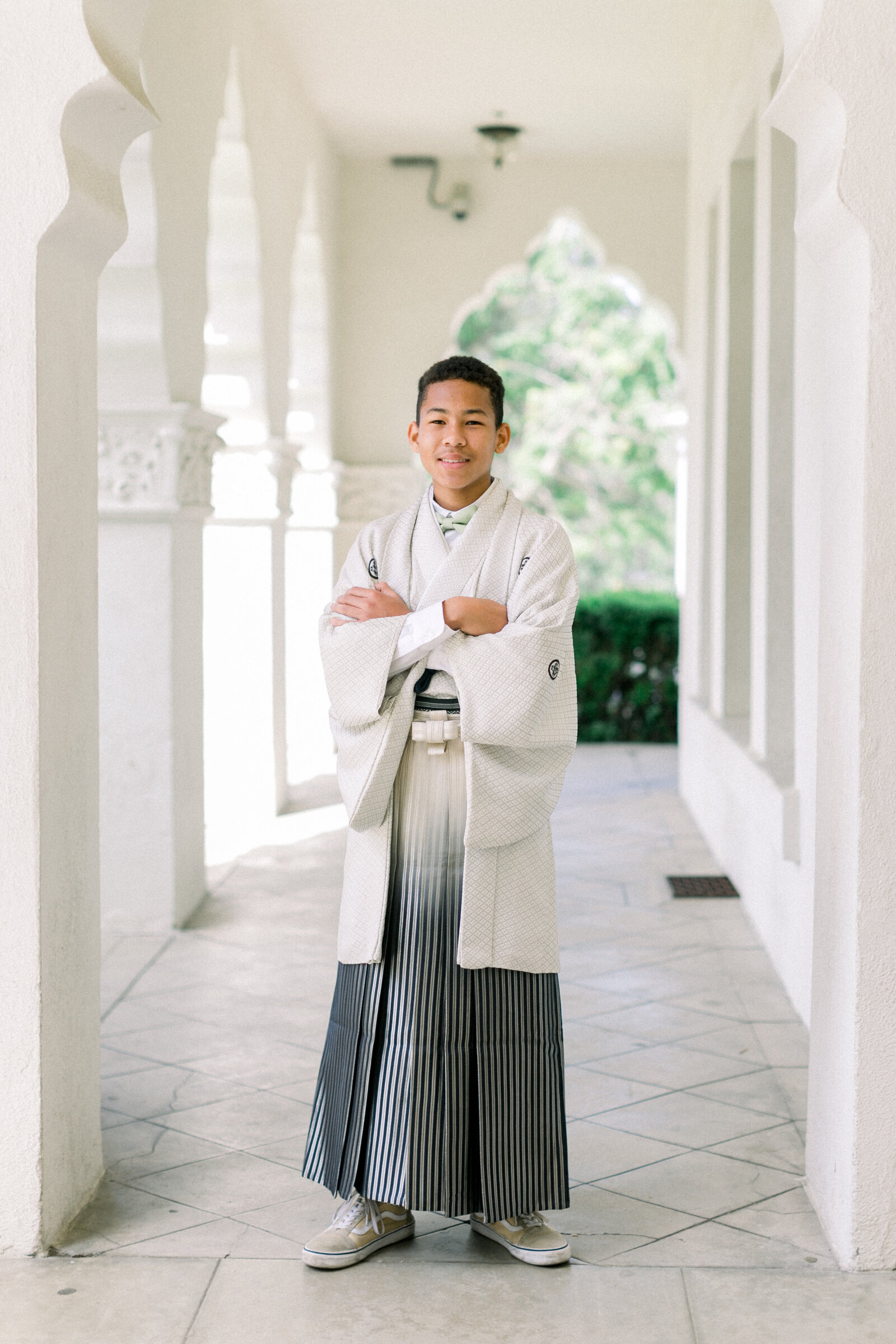 Confident young man in a white montsuki haori and striped hakama standing proudly during Seijinshiki at Brand Park Glendale, kimono rental Los Angeles | ロサンゼルス・ブランドパークでの成人式、白い紋付羽織と縞袴で堂々と立つ青年のポートレート