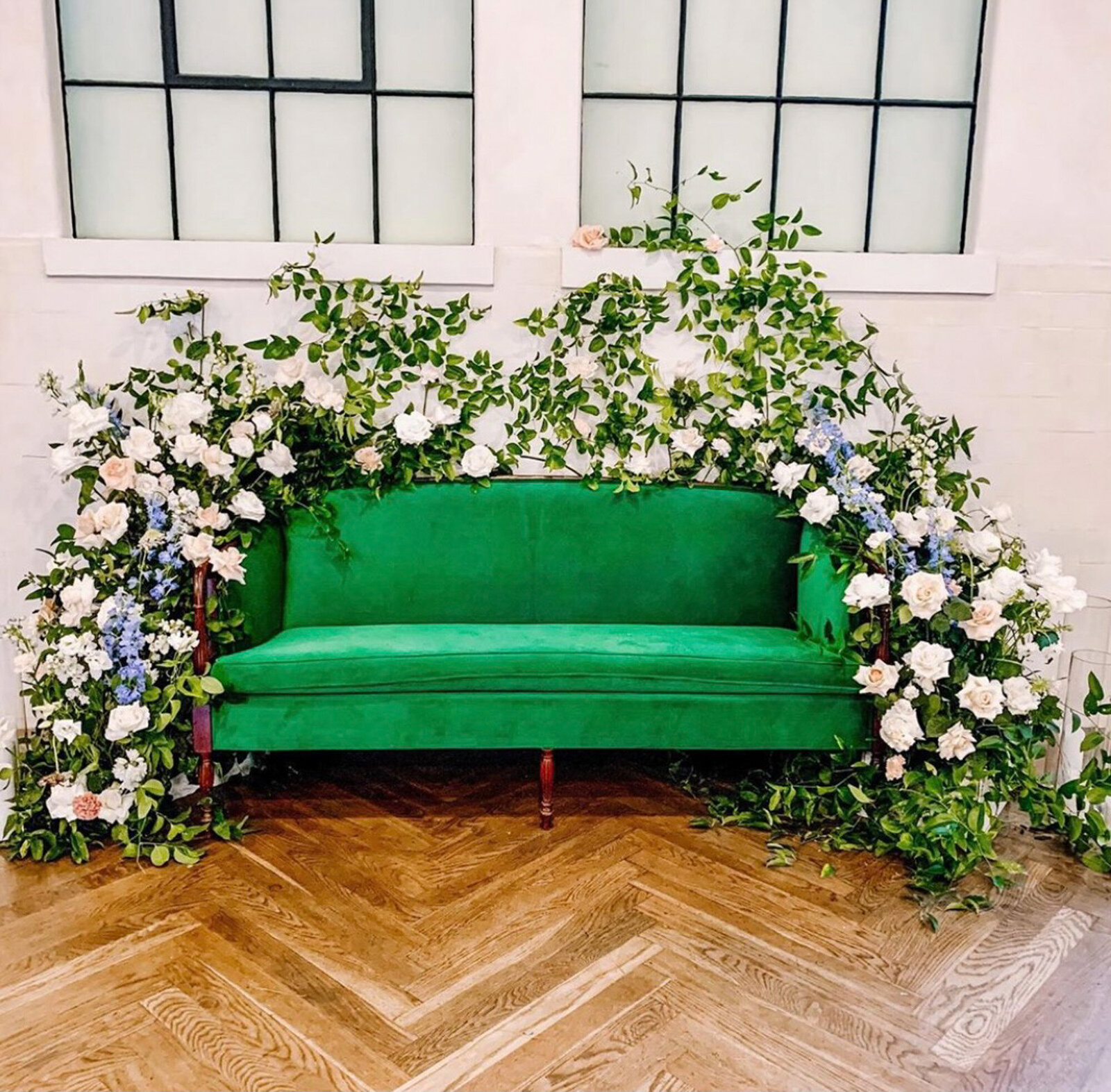 emerald couch decorated with florals for luxury wedding