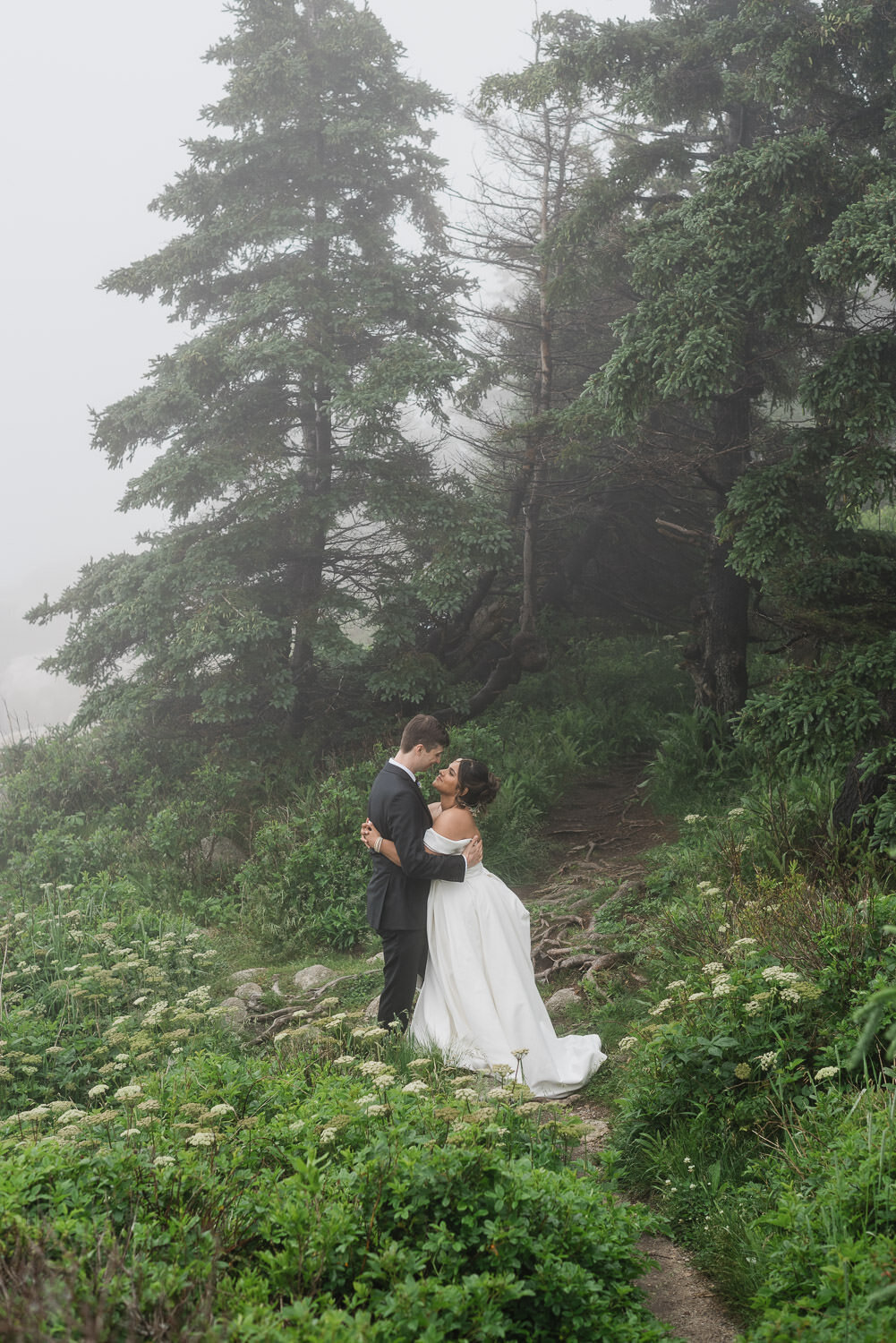 Intimate moment between bride and groom in misty forest by the sea in Nova Scotia.