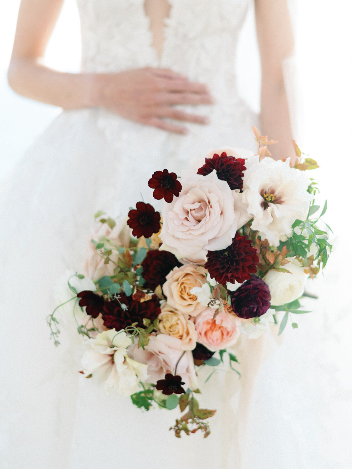 Close up of bridal bouquet with pink, peach and burgundy florals.