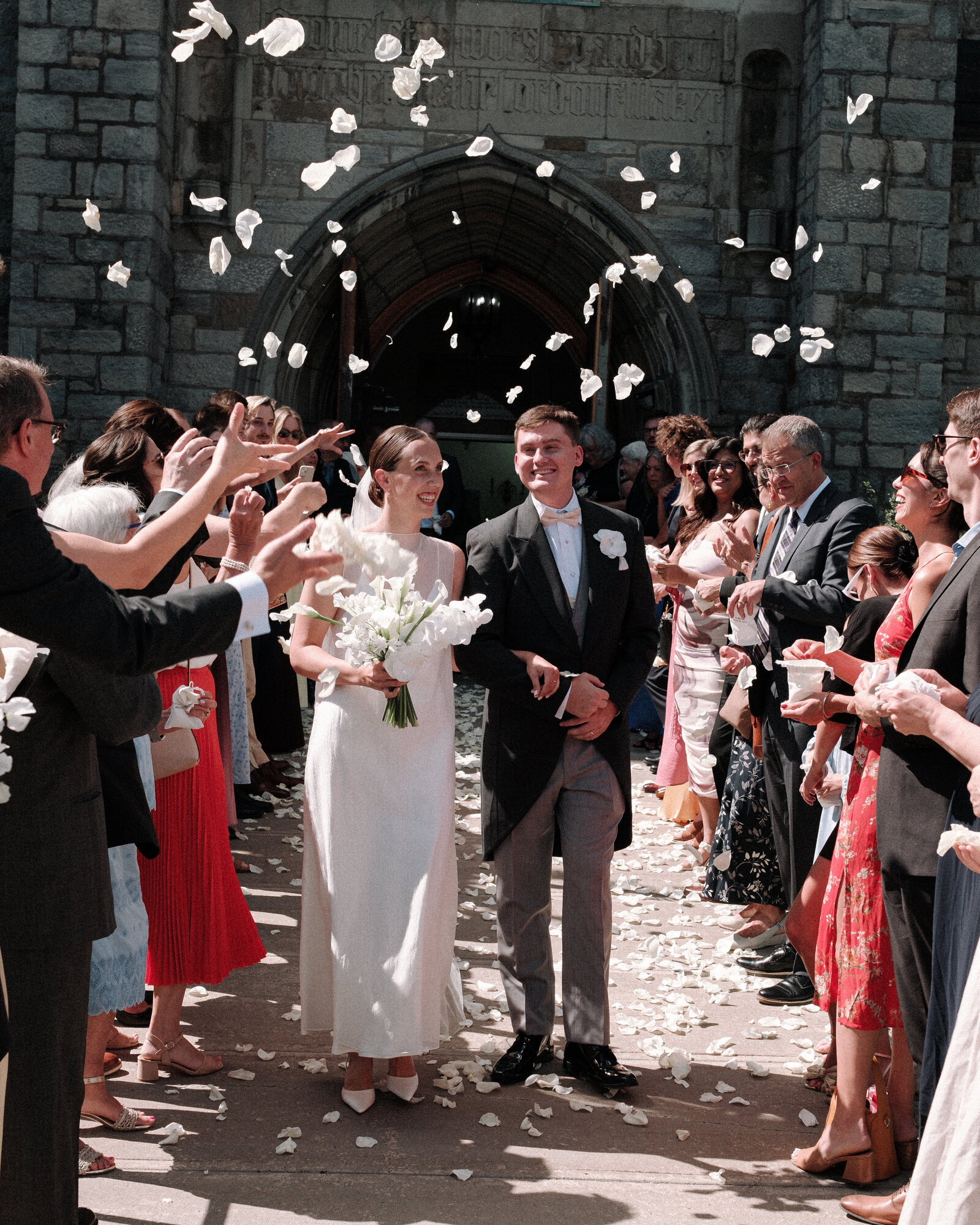 Joyful newlyweds exiting the church amid a shower of flowers, celebrating their love with friends and family