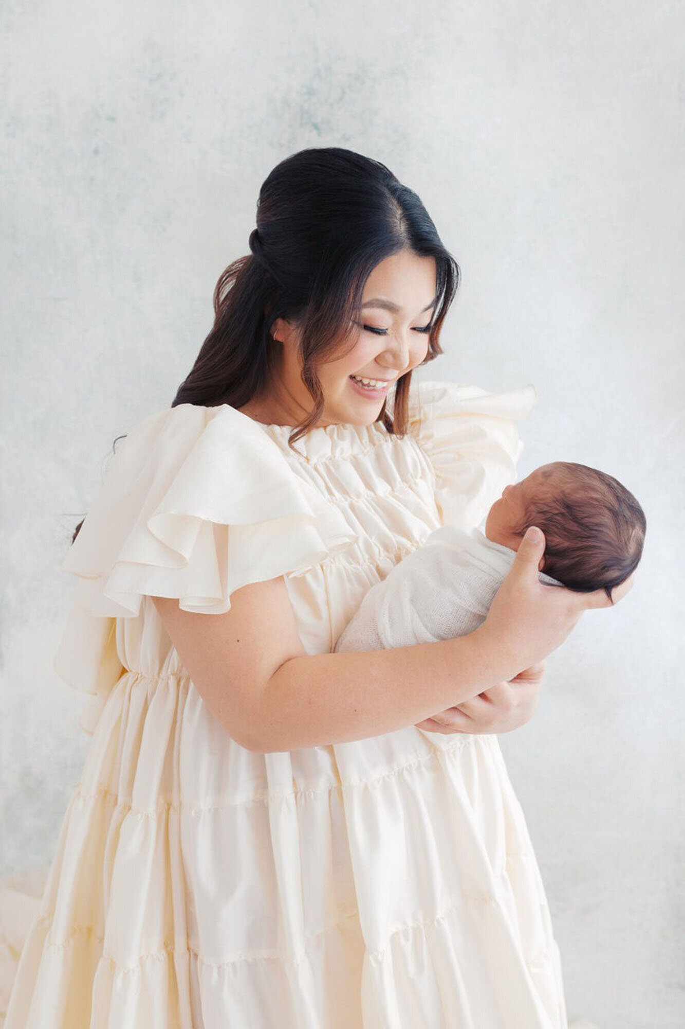 Swaddled baby posed in mom's arms during Bay Area newborn photography studio session.
