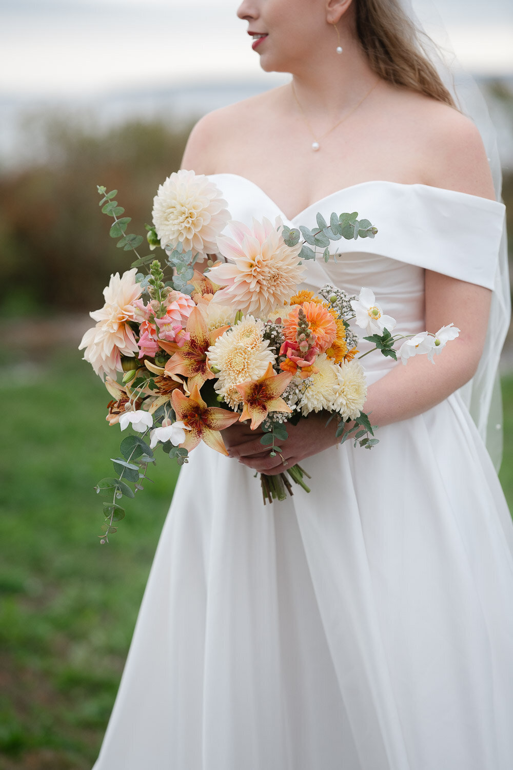 bride holding vibrant fall bouquet