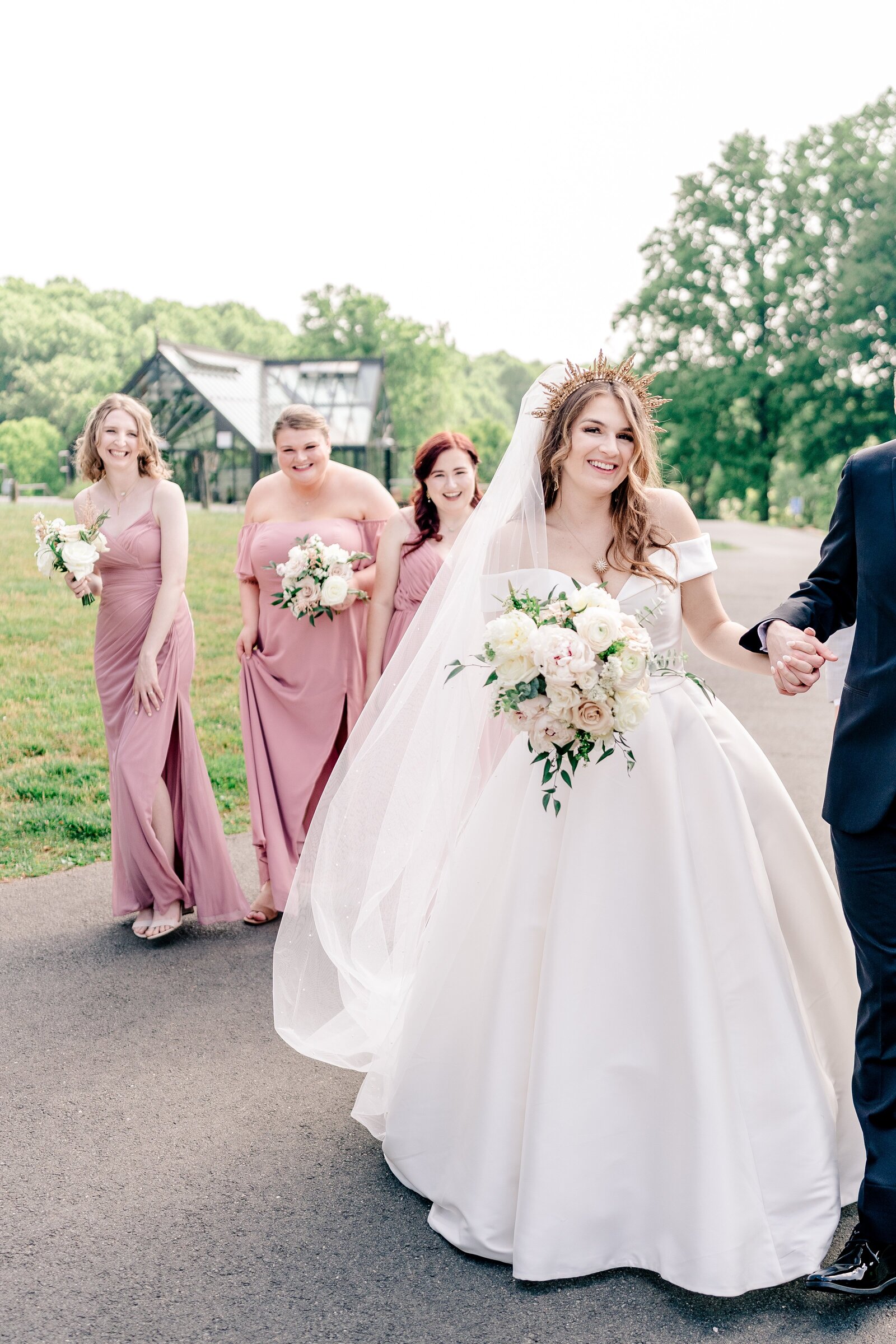 A bride and her bridesmaids as they walk together on her wedding at Meadowlark Botanical Gardens in Northern Virginia