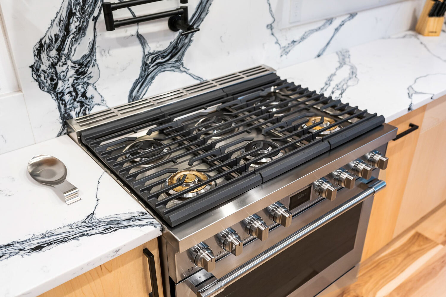 Stainless steel gas stovetop with marble backsplash in a kitchen