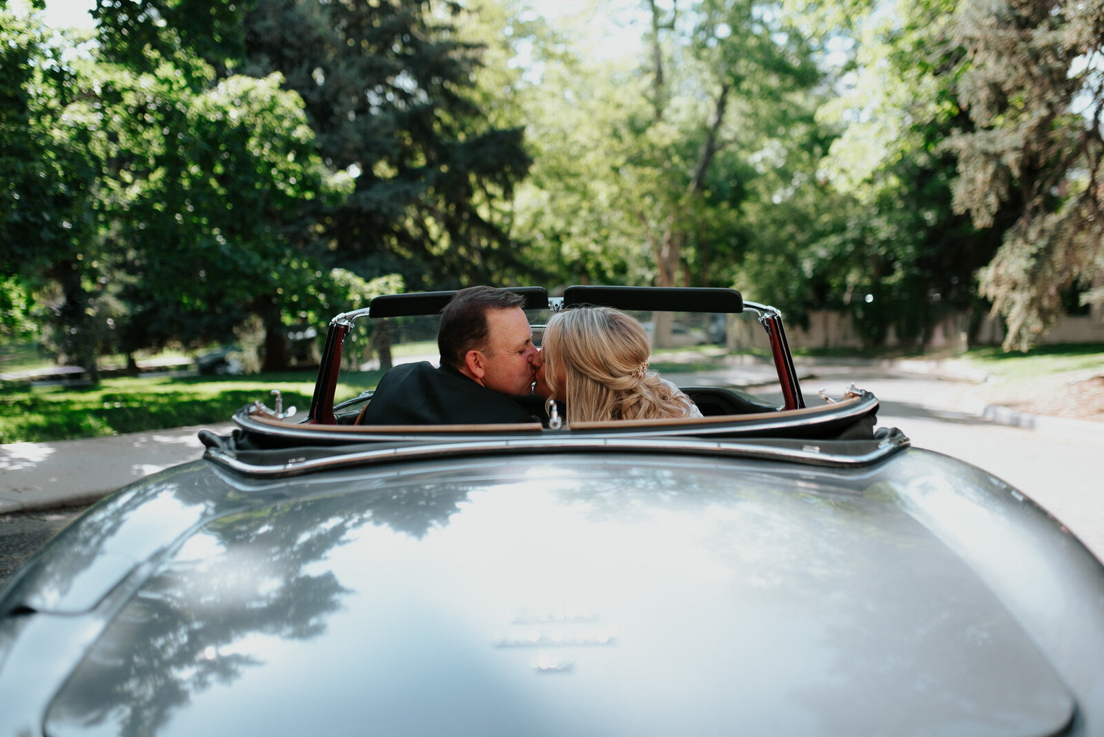 bride and groom driving away in classic sports car from the grant humphreys mansion