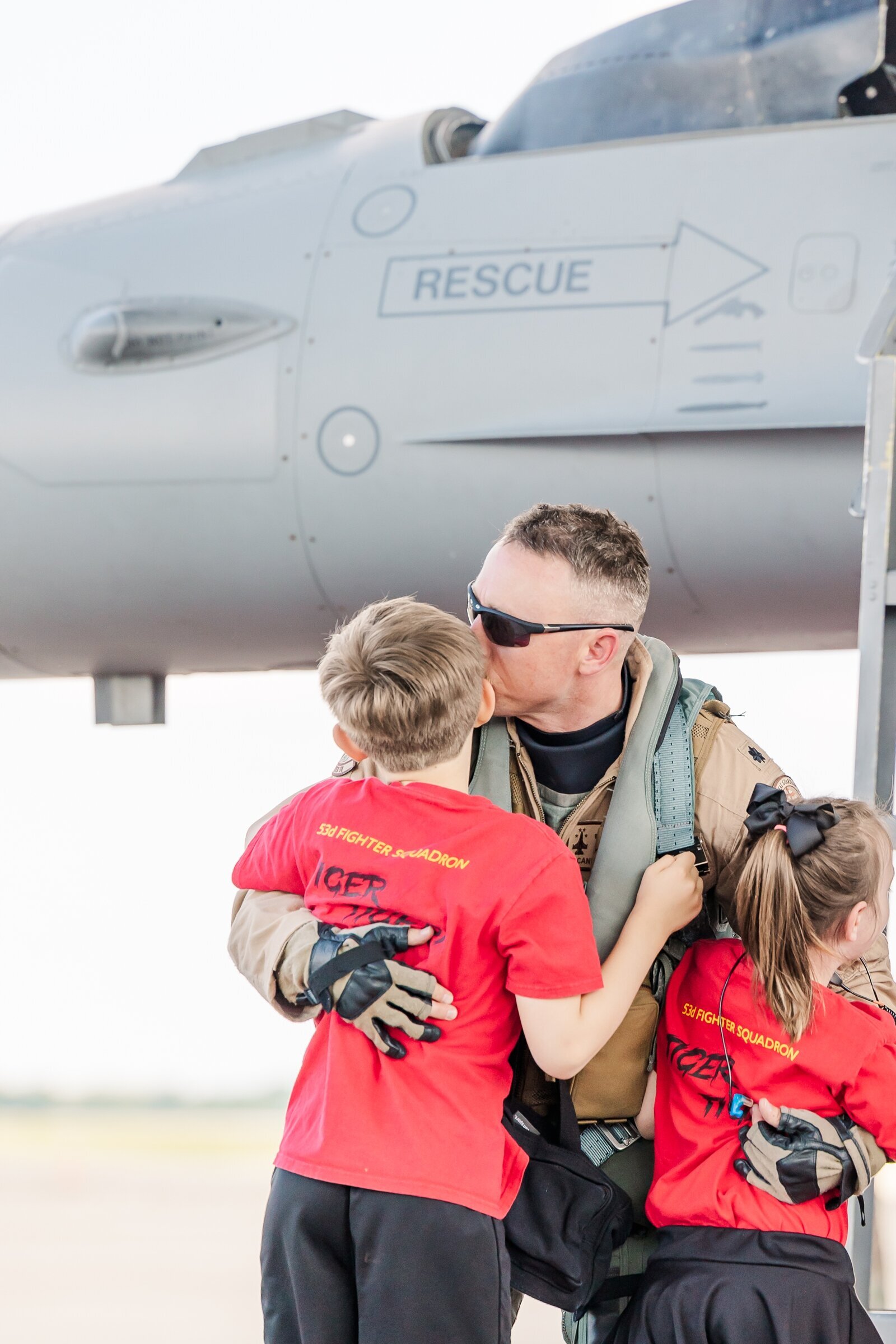 Pilot dad kissing his kids at his deployment homecoming