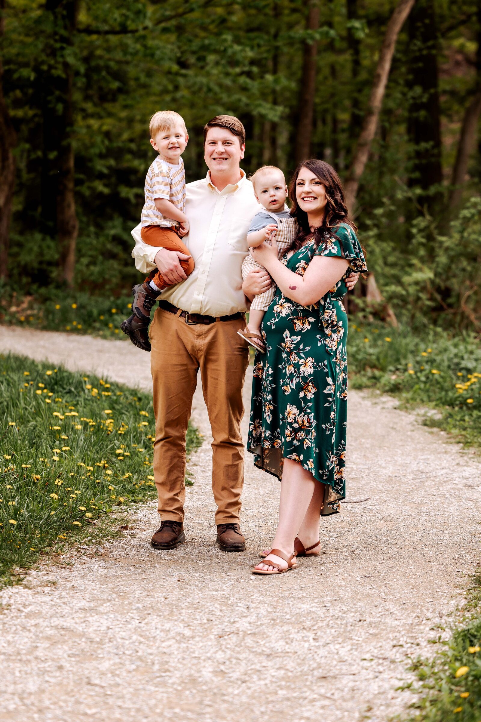 Family poses for a photo along a gravel path leading into the forest