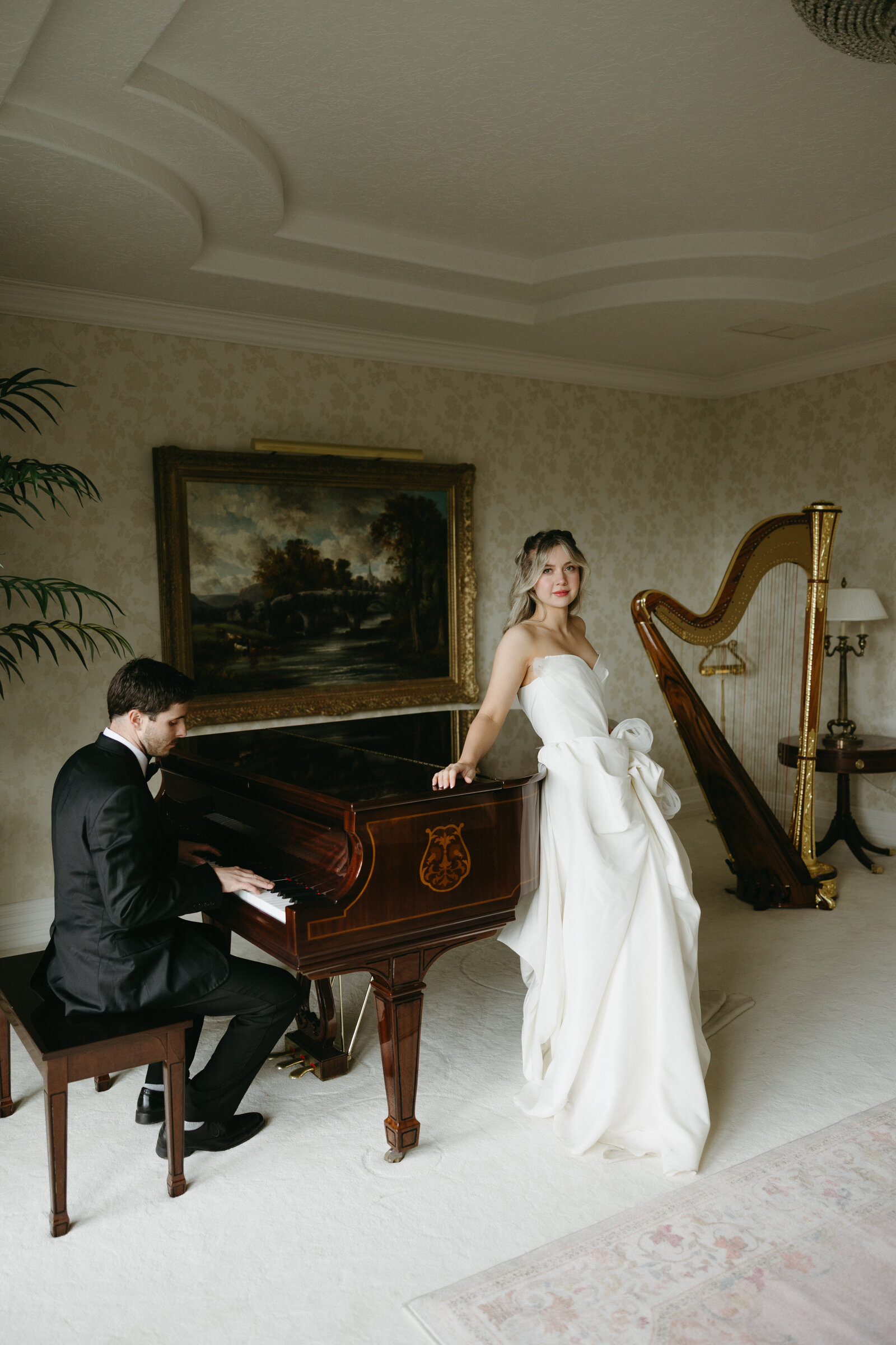 A bride is leaning on a piano as her groom plays her a song at a beautiful wedding venue in Vancouver. 