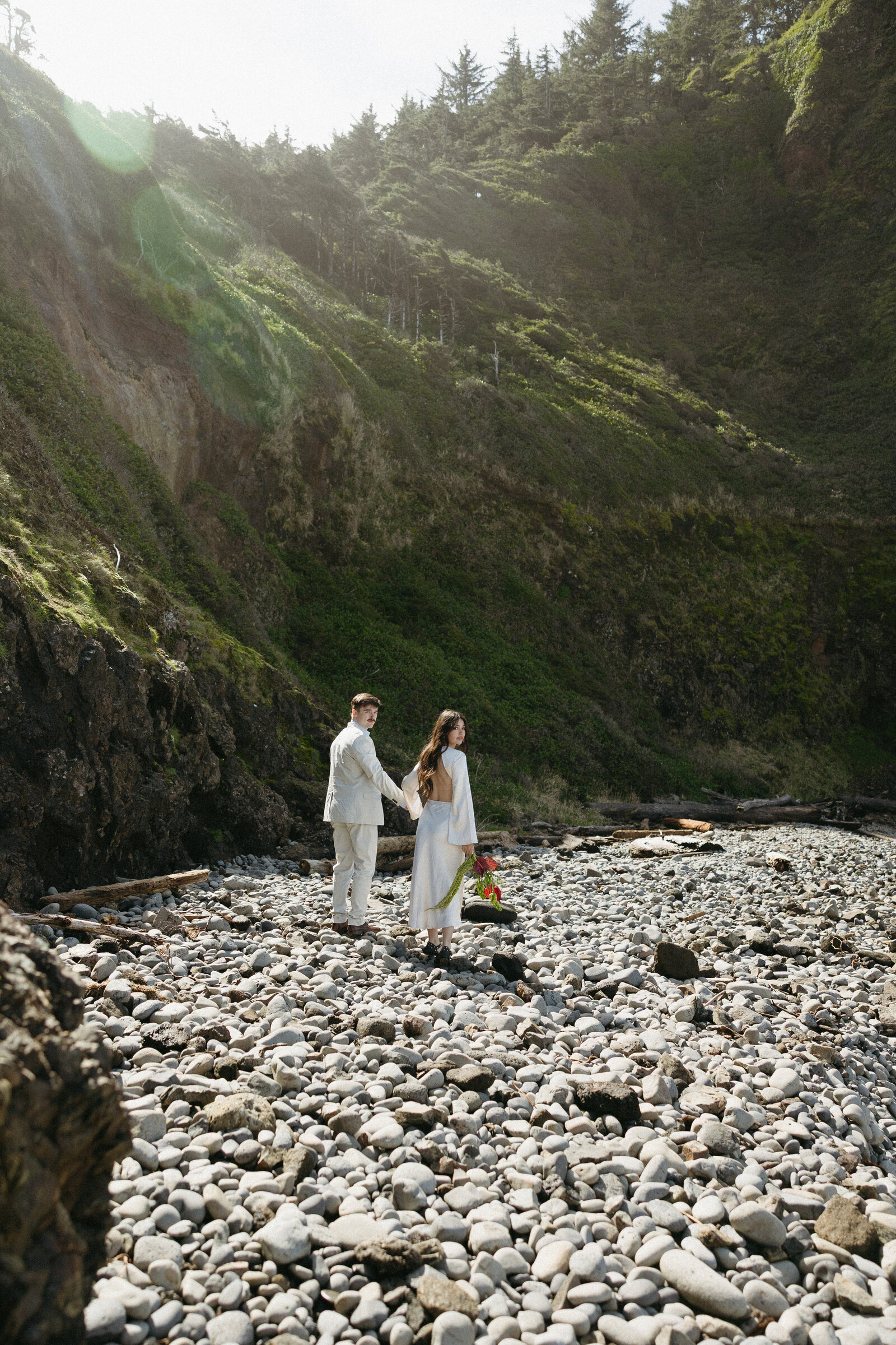 A bride and groom walks along a rocky beach in Tofino after eloping.