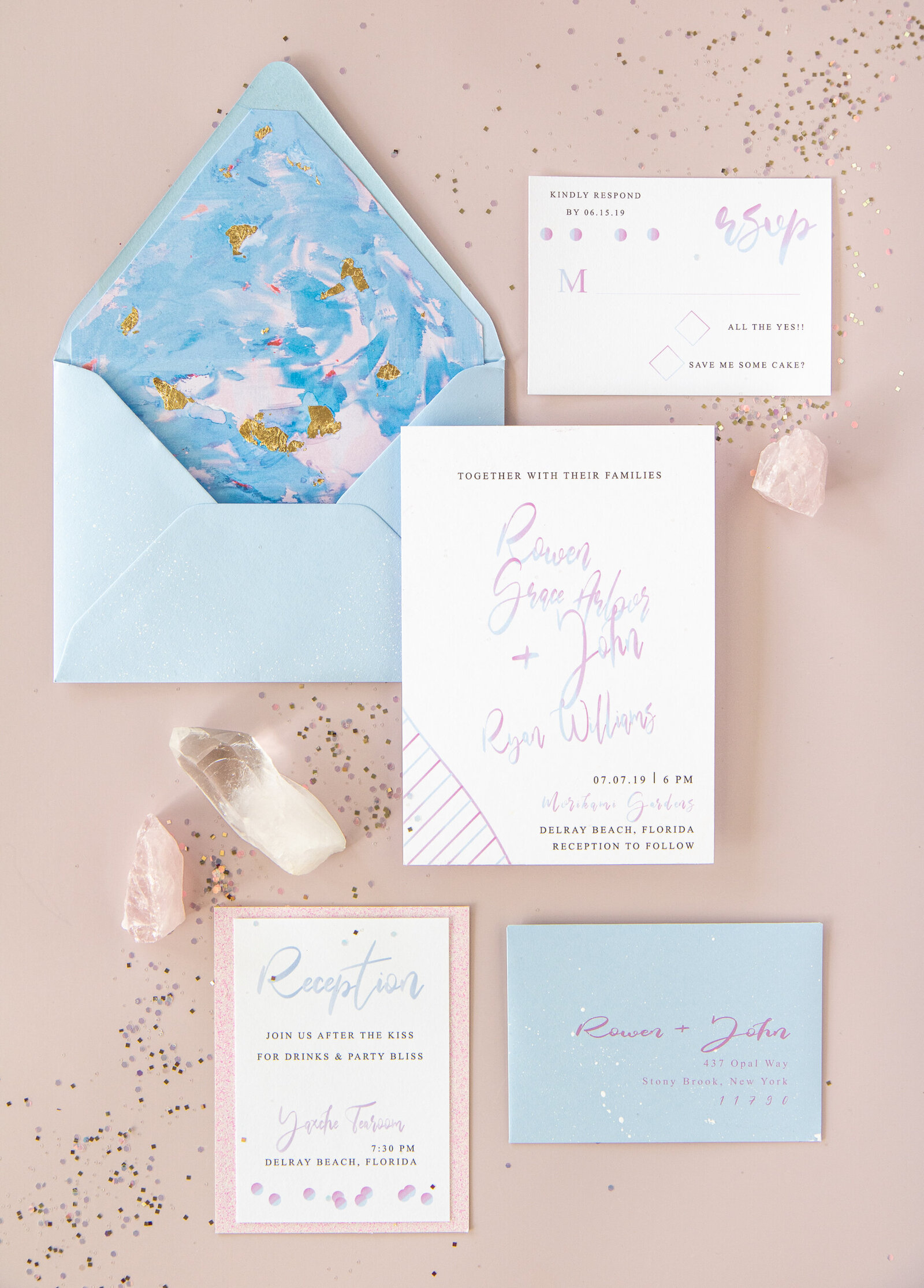 An invitation flatlay photo of a pastel invitation suite surrounded by rose quartz crystald