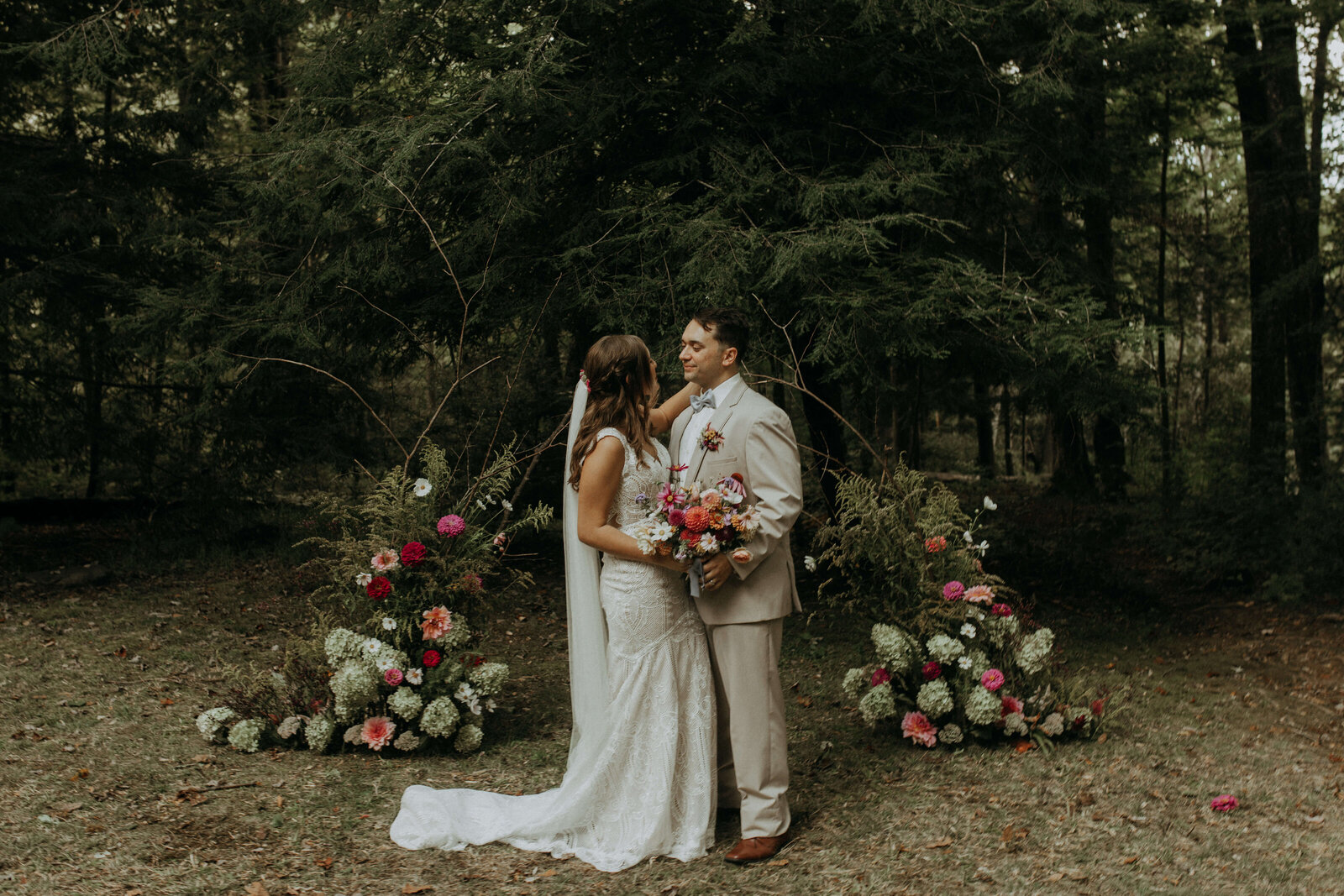 bride and groom with rustic floral arch