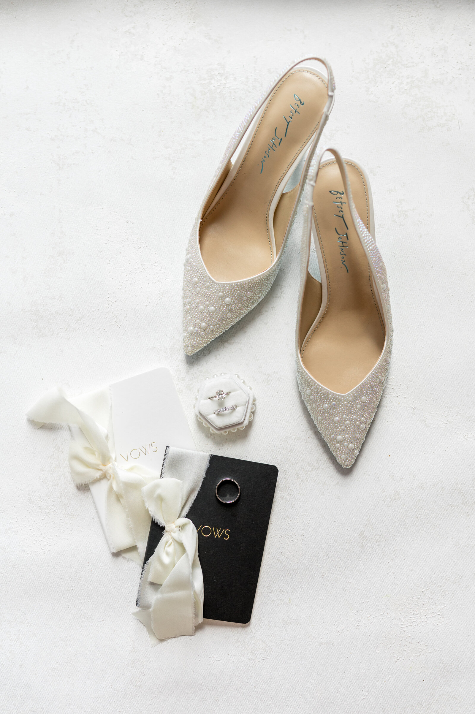 Sparkling Betsey Johnson bridal shoes, vow books and rings flatlay — luxury wedding detail photography by Sarah Surette Photography