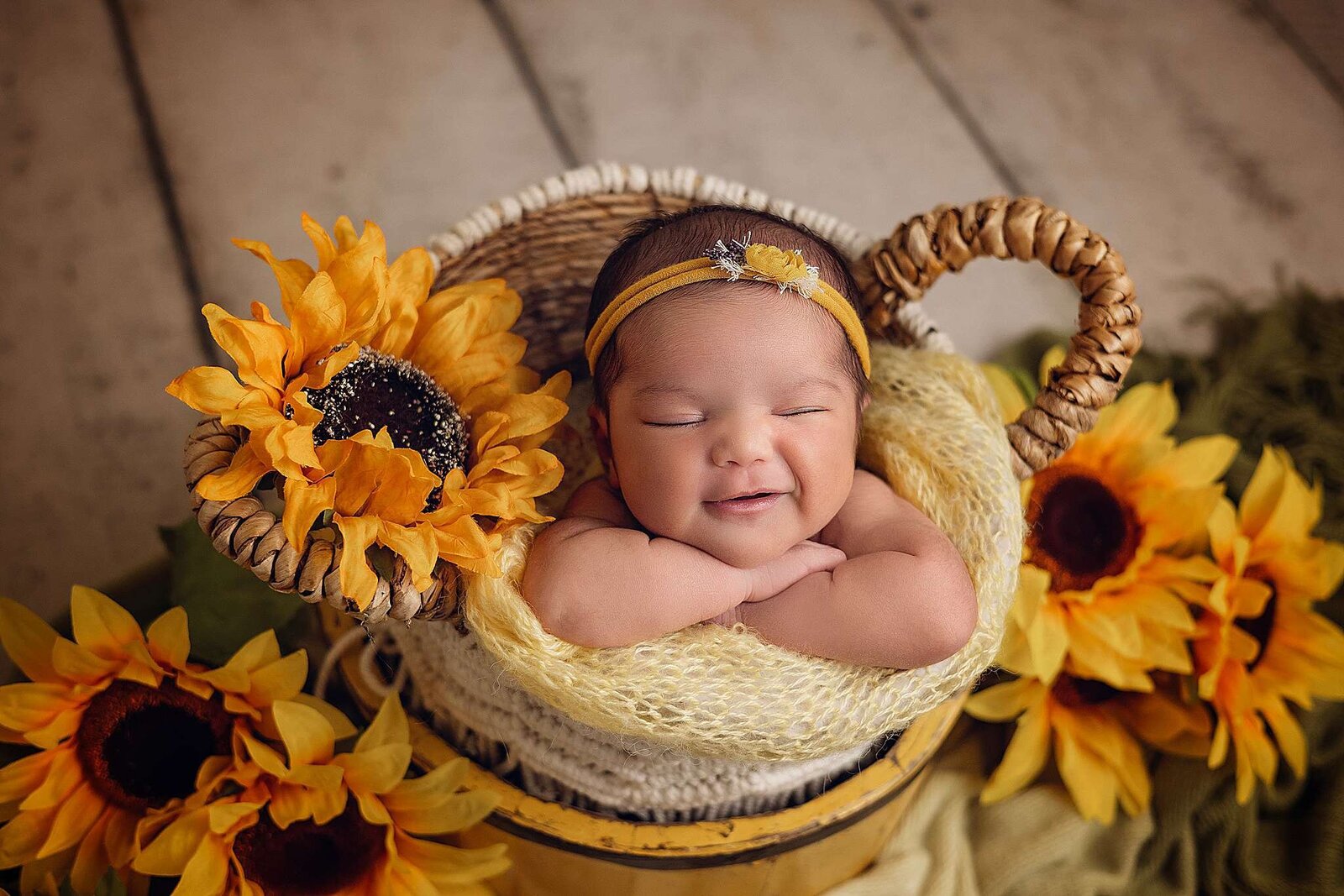 A newborn girl nestled in a basket surrounded by vibrant sunflowers, captured by Bia Schaefer, Orlando newborn photographer.