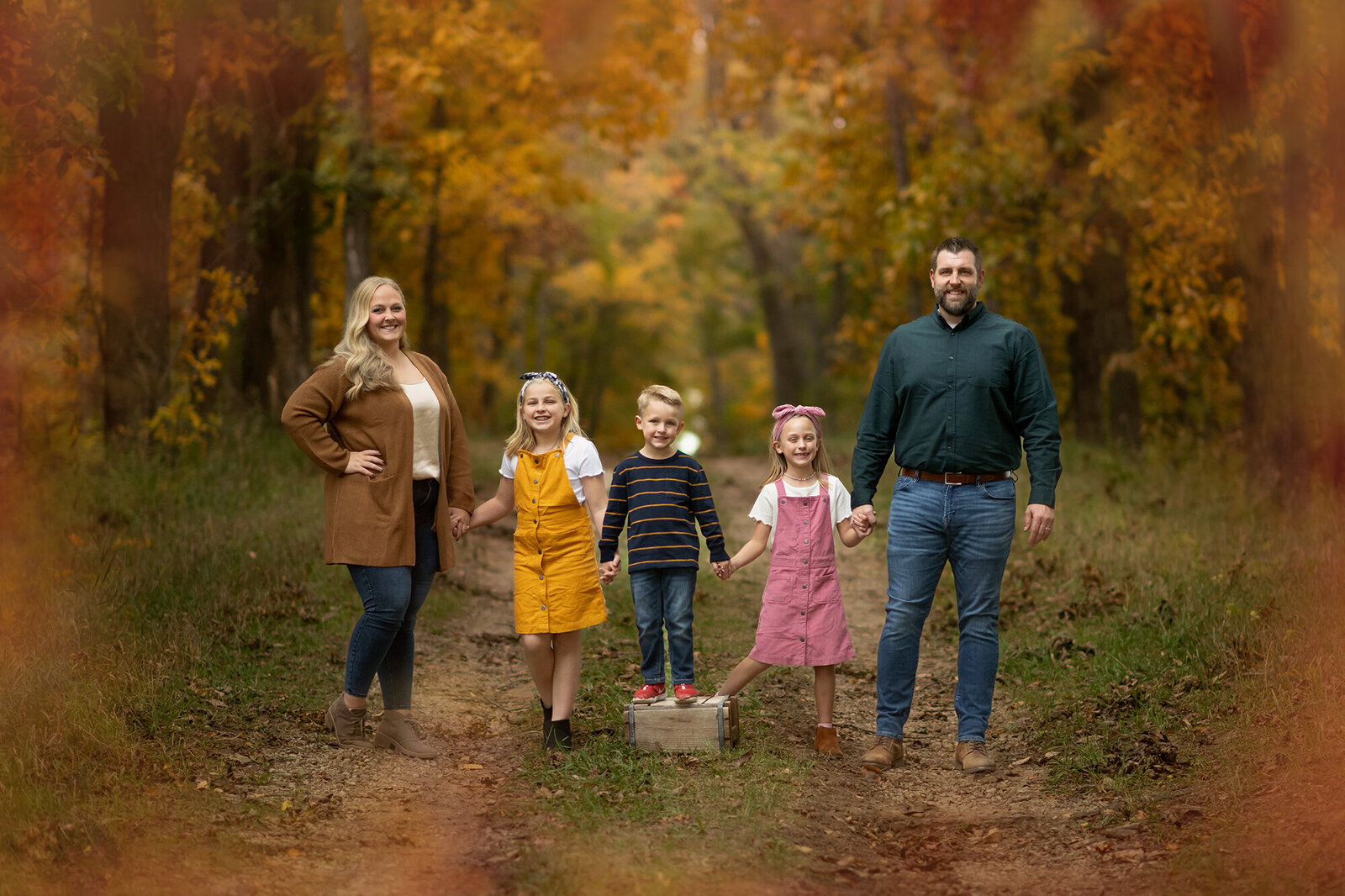 Whole family holds hands and stand on a path in forest