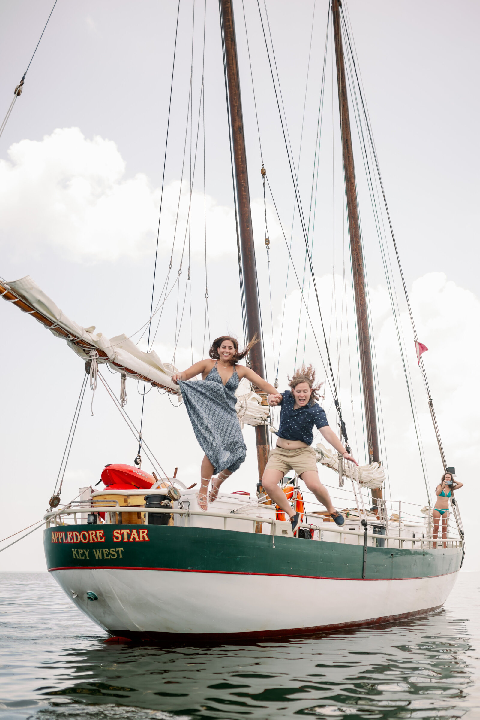 engaged couple jumping off the back of a sailboat into the water in Key West, FL