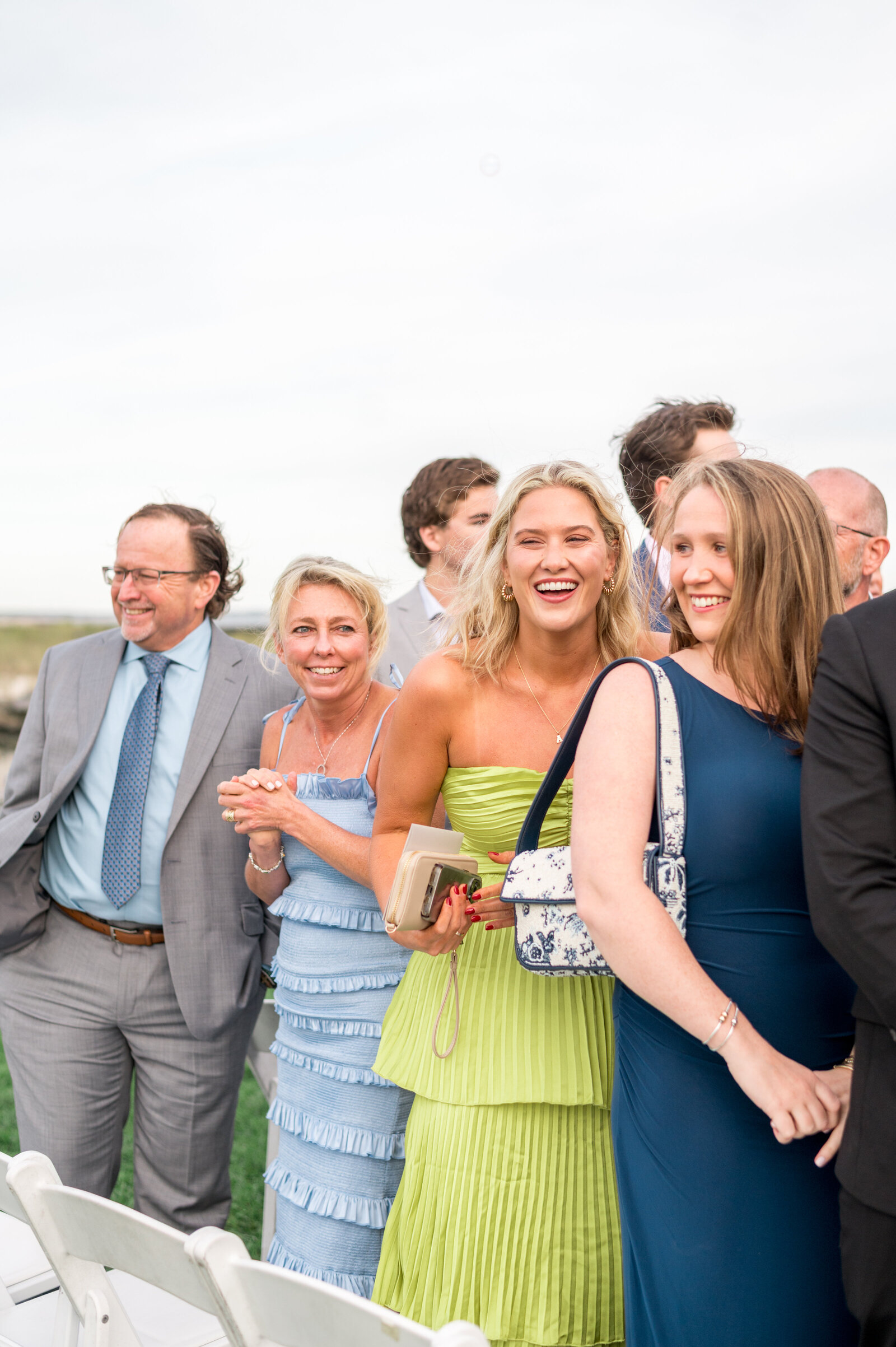 Wedding guests smiling and enjoying outdoor ceremony at Wychmere wedding — candid, joyful photography by Sarah Surette Photography.